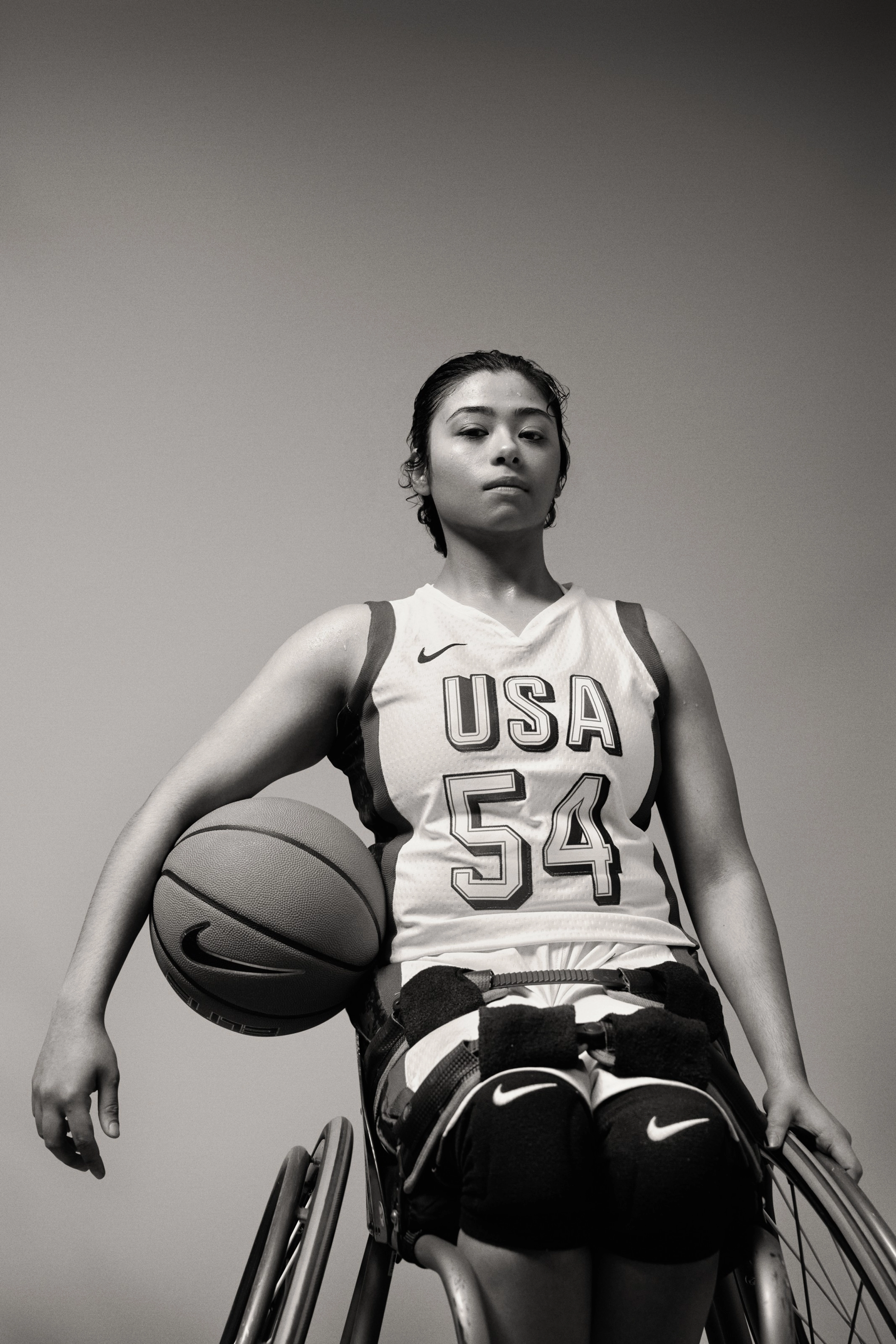 Black and white photo of Ixhelt Gonzalez holding a basketball under her arm.