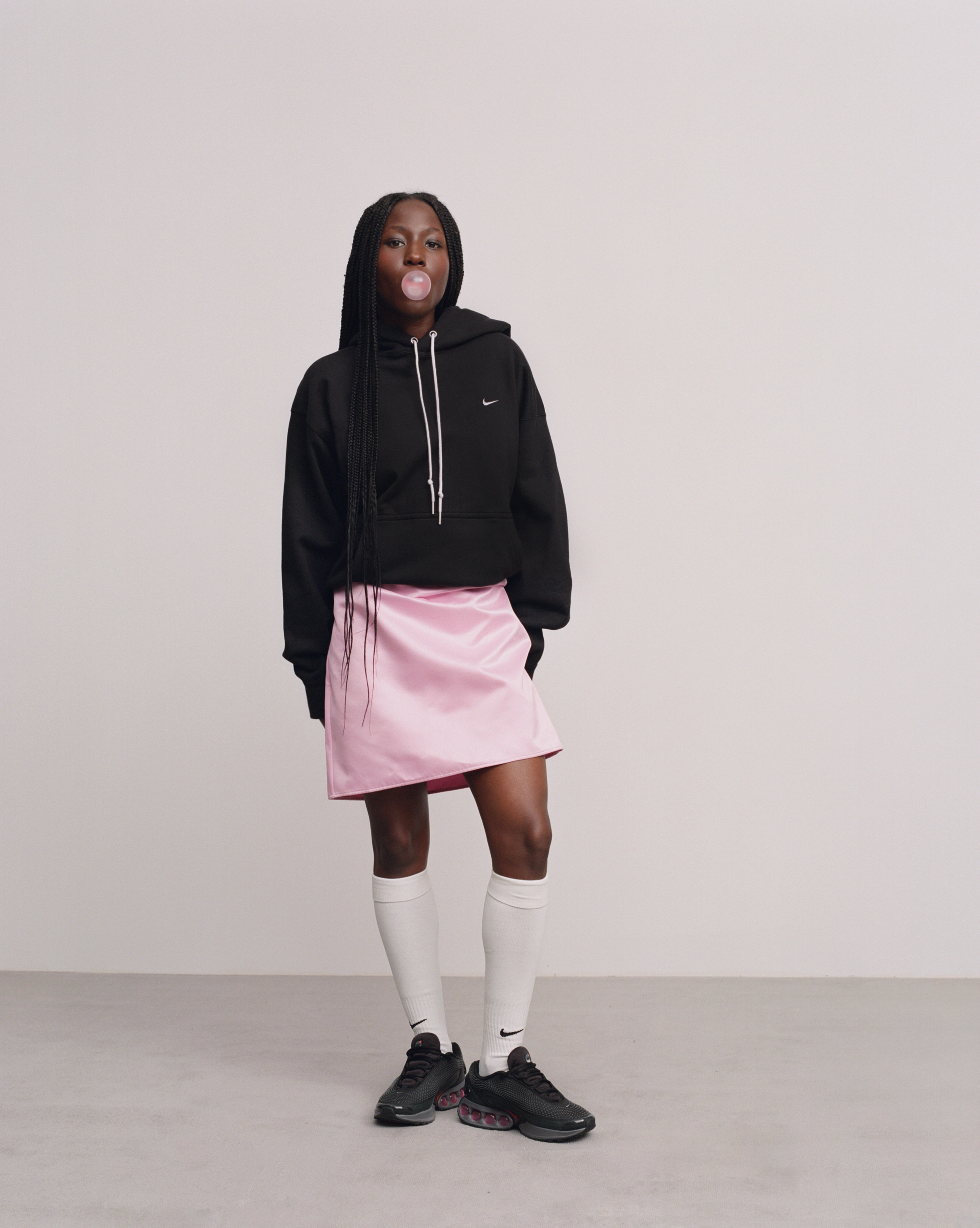 Female model wearing the Nike Air Max Dn in the all night colorway while blowing a bubblegum bubble.