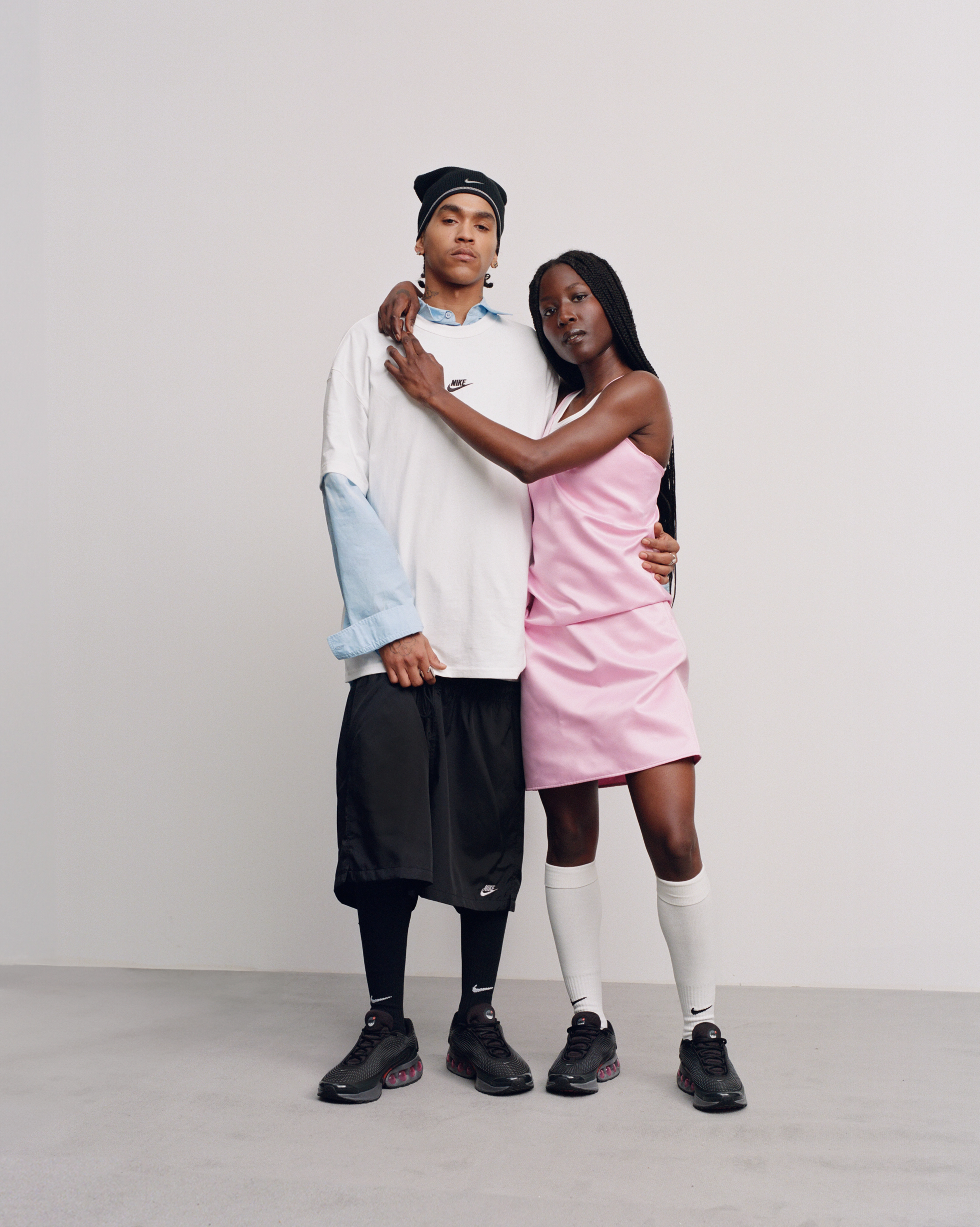 Female model with her arms wrapped around the male model and both wearing the Nike Air Max Dn in all night colorway.