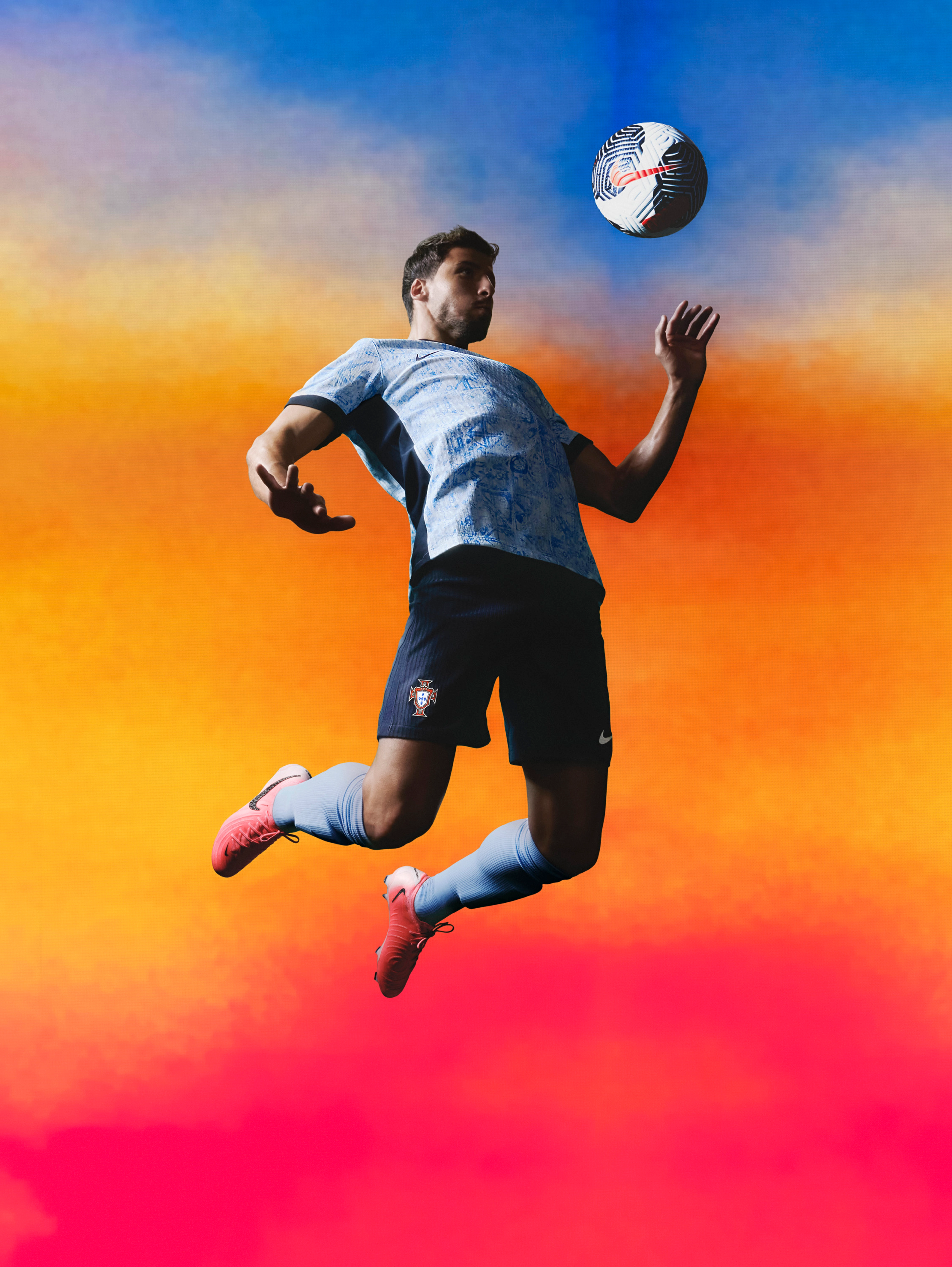 Athlete bouncing a soccer ball off their chest wearing a white soccer jersey with black sides, a black collar, black cuffs, and a faded light blue triangle pattern, as well as matching black shorts, each with a Nike swoosh and team logo on the chest and legs. They are also wearing light grey socks.