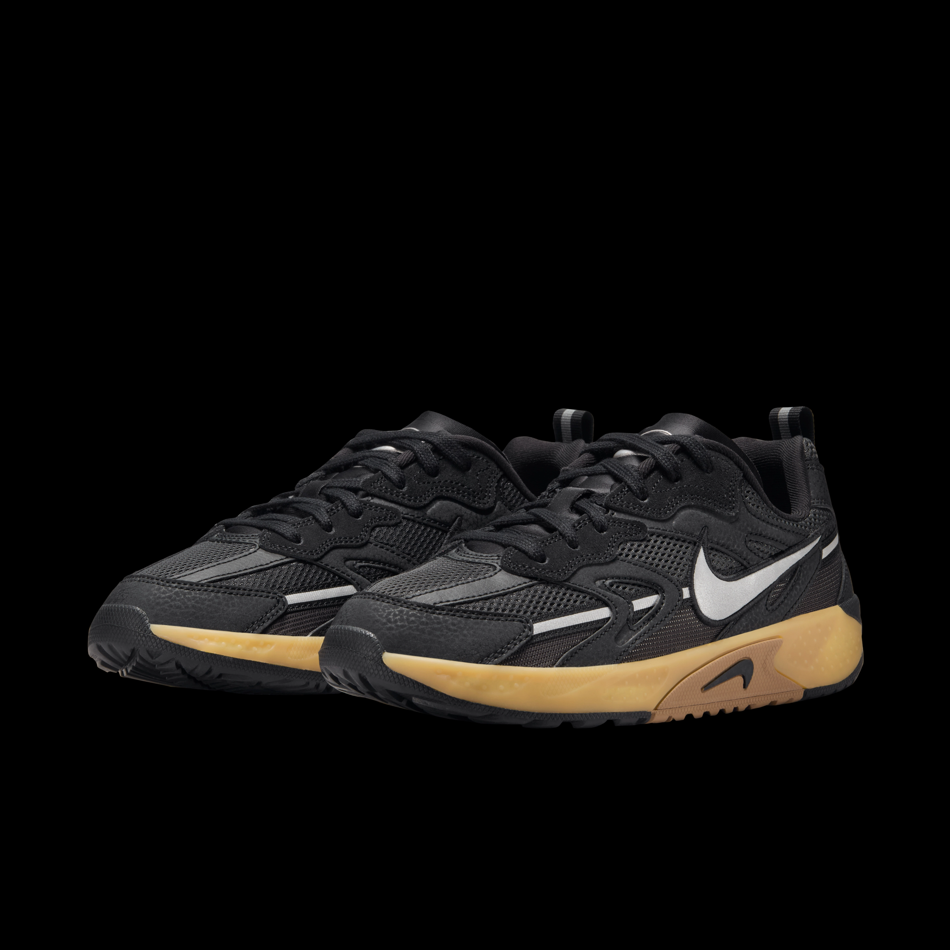 Side view of a pair of Nike Jam sneakers, with black uppers, gum midsole, and silver Nike Swoosh, sits on a black background.