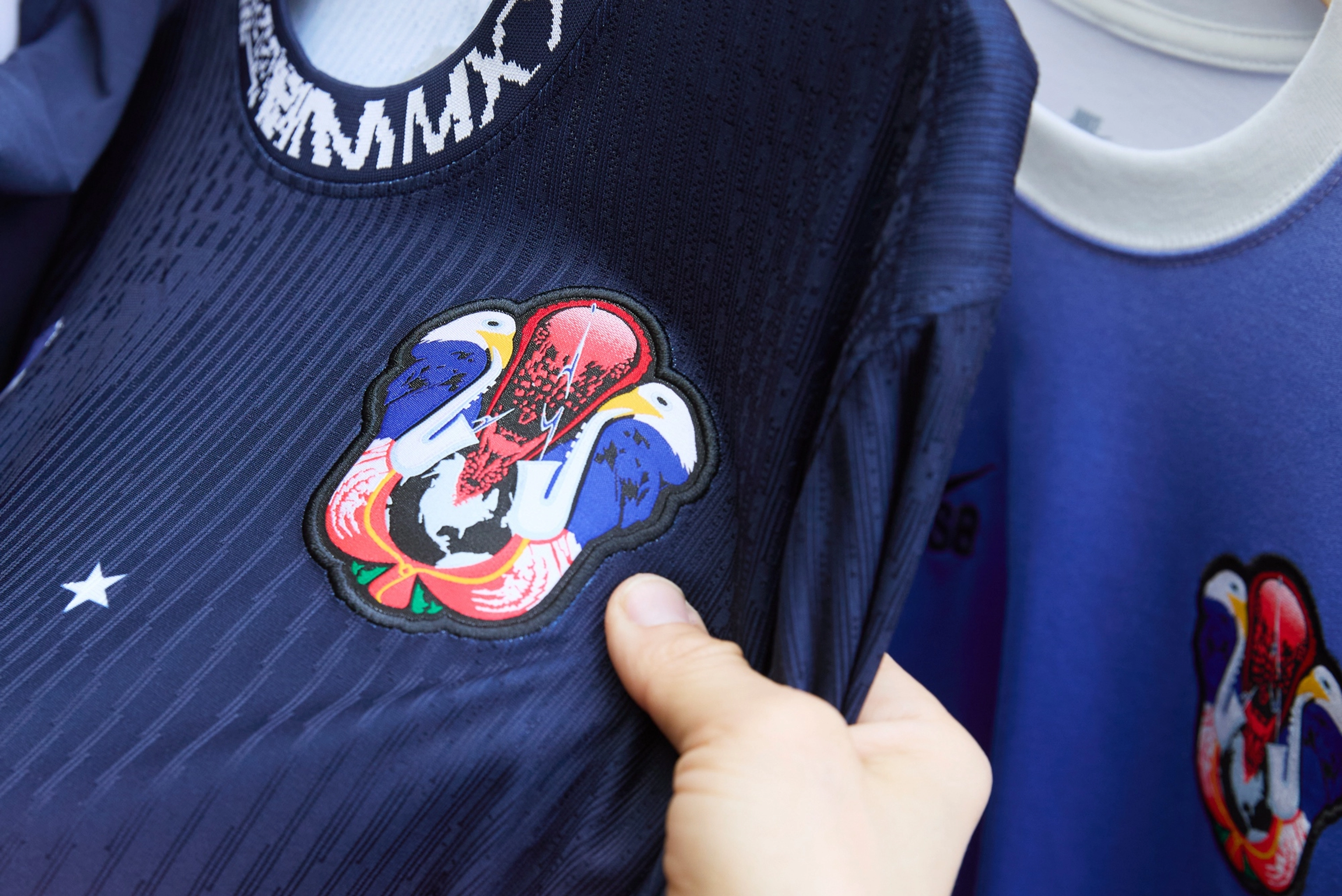 Close up view of Alexis Sablone's hand holding the shirt of USA skateboarding federation kit featuring the crest.