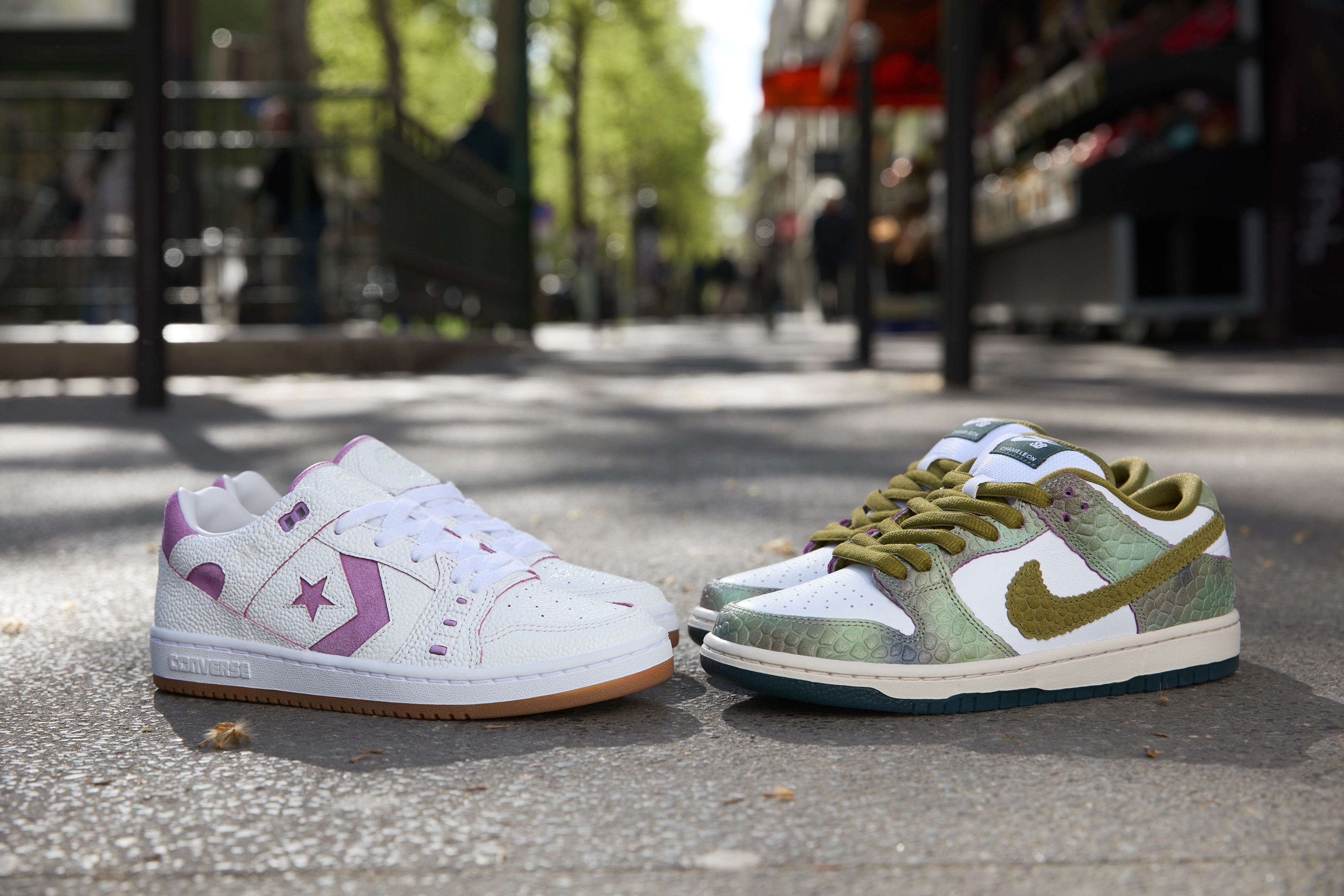 Two pairs of shoes facing each other on an outdoor street. On the left, the Converse CONS AS-1 Pro in purple and on the right the Nike SB Dunk Low in oil green and desert moss.