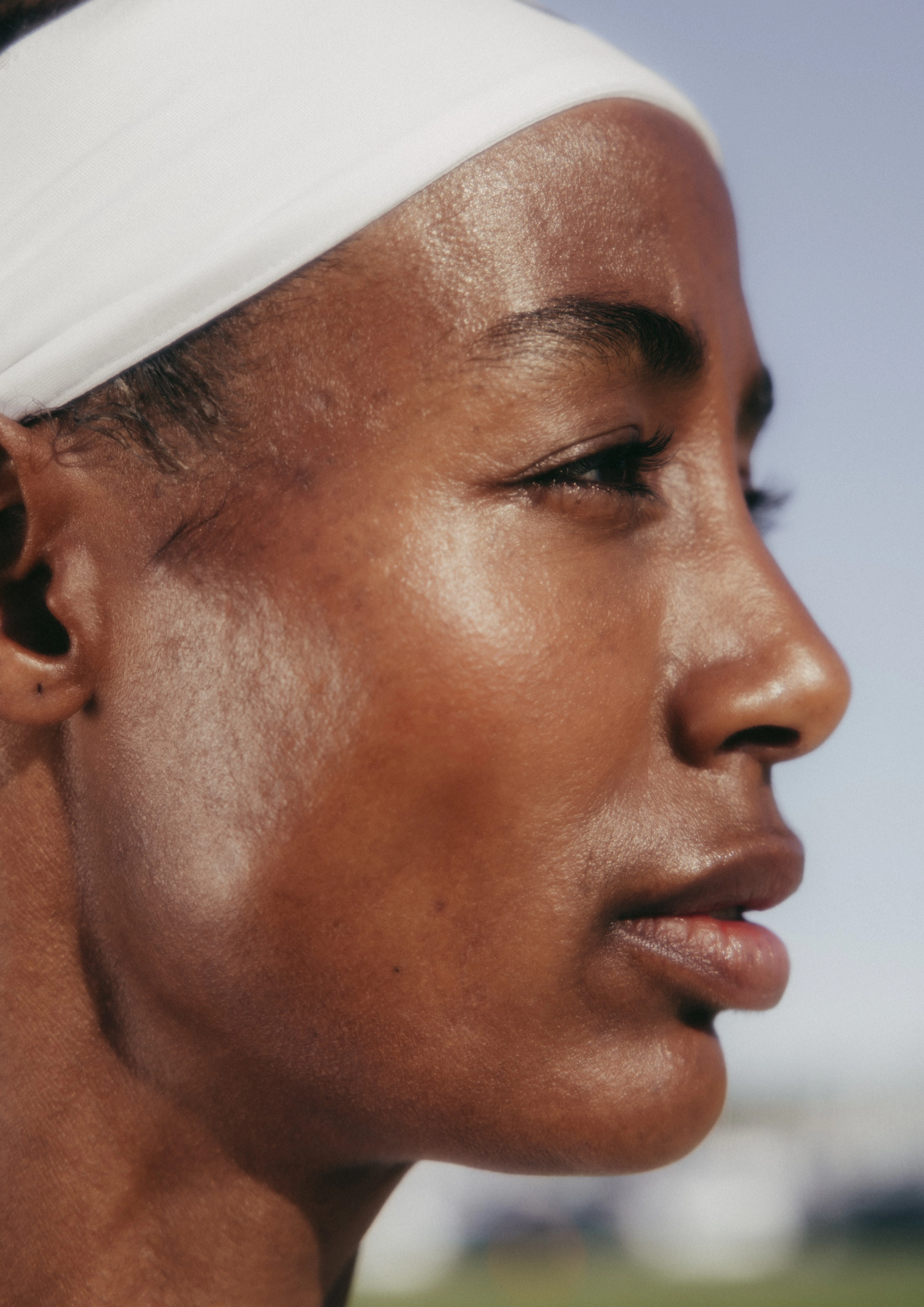 Close up side view of Sifan Hassan's face. She wears a white Nike headband and looks to the right.