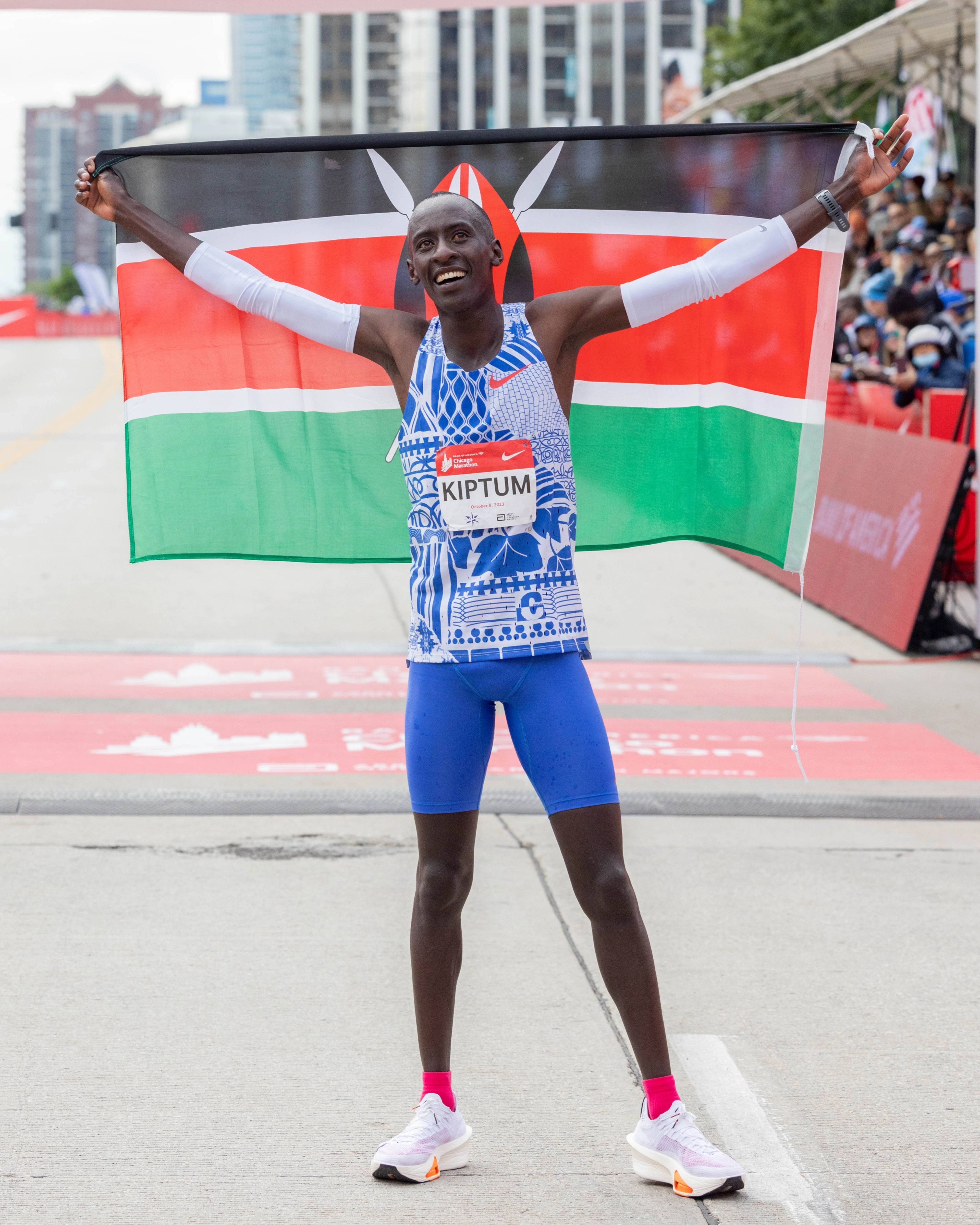 Kelvin Kiptum holding up the Kenyan flag behind him and wearing the Nike Alphafly 3 after setting the new marathon world record at the 2023 Chicago Marathon