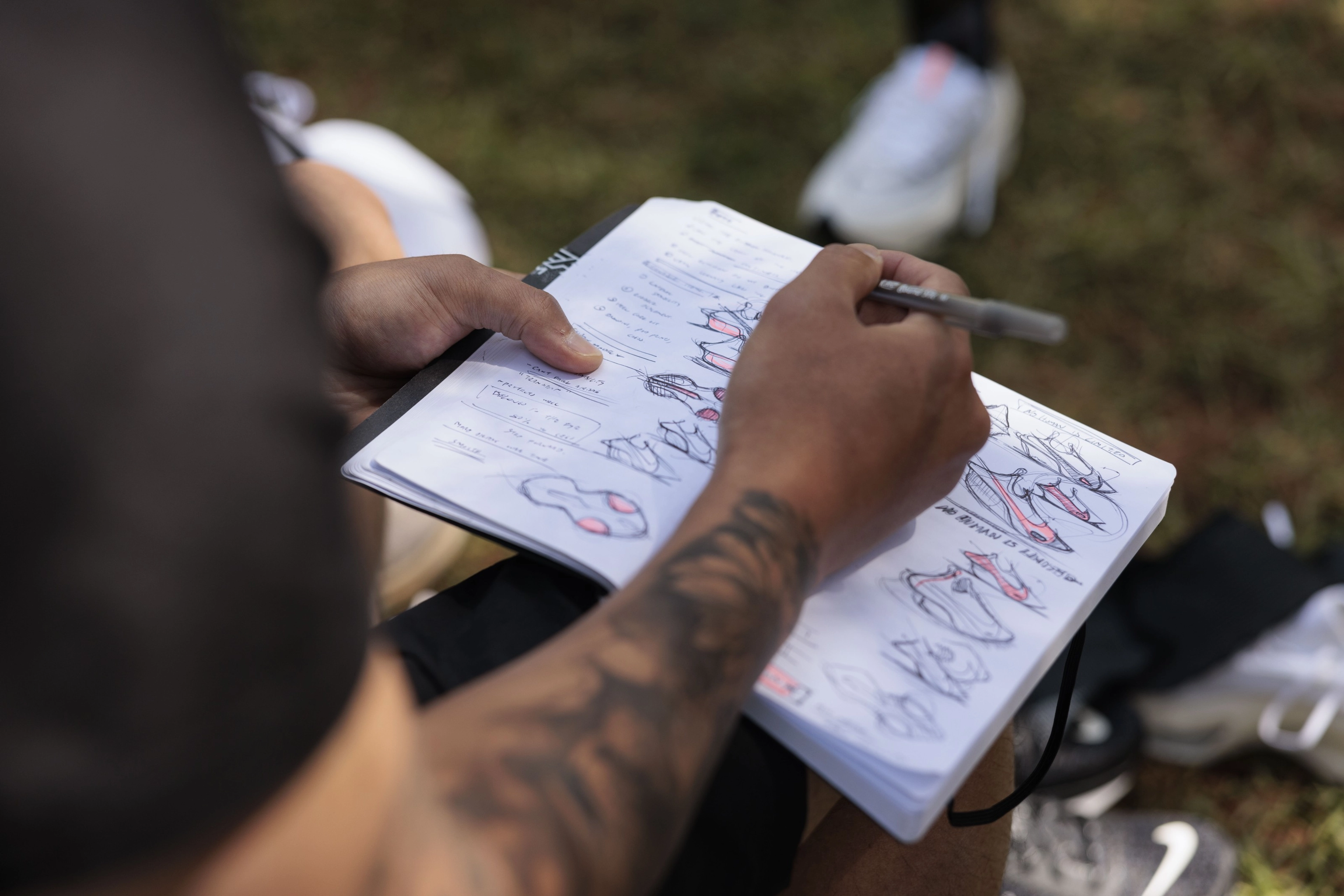 An artist sketching with a pen on a notebook the Nike Alphafly 3 from various angles and viewpoints.