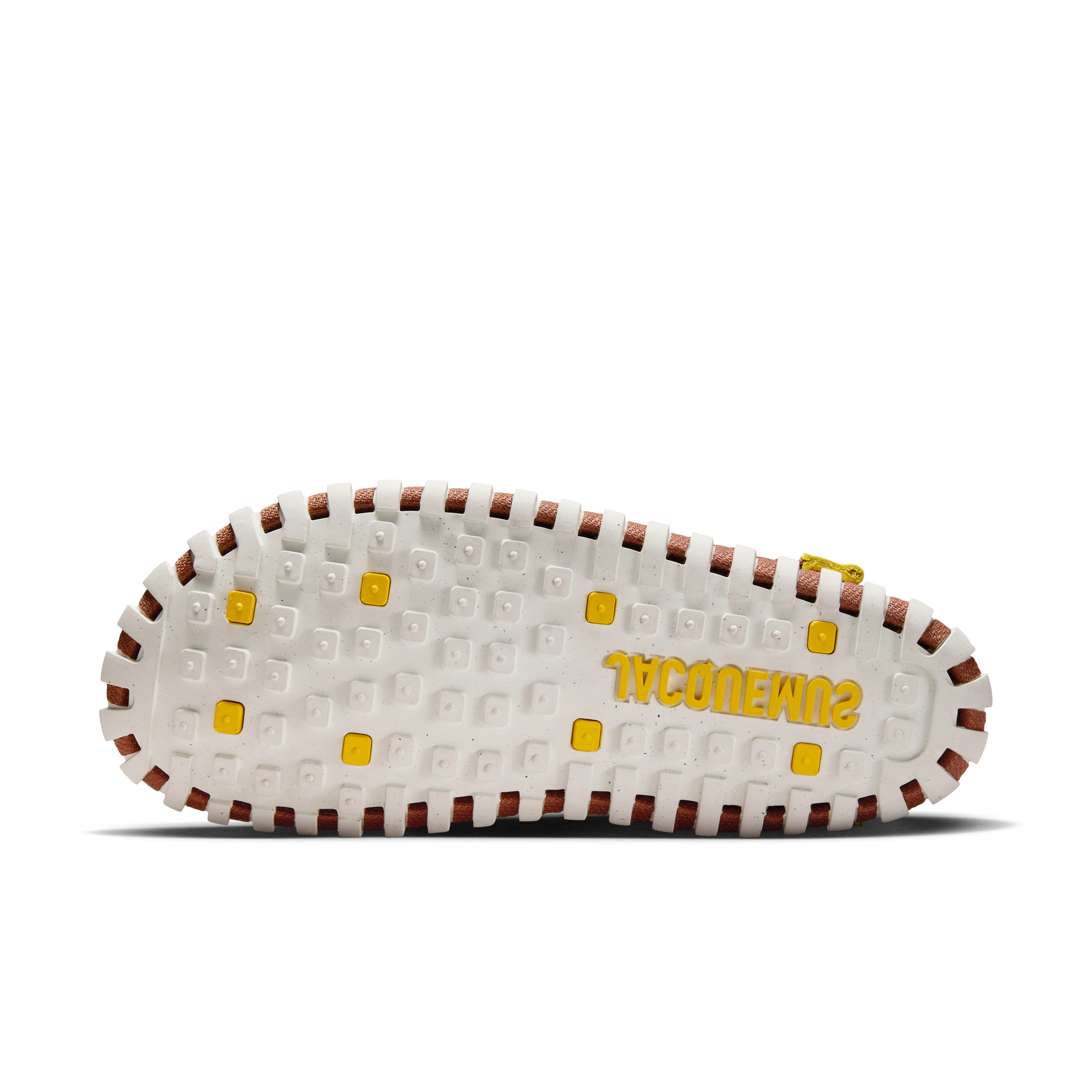 Underside view of a Nike x Jacquemus J Force 1 Low LX SP, with a white sole with yellow details, including yellow Jacquemus logo. We see brown webbing details where the shoe layers are held together. The shoe floats on a black background.
