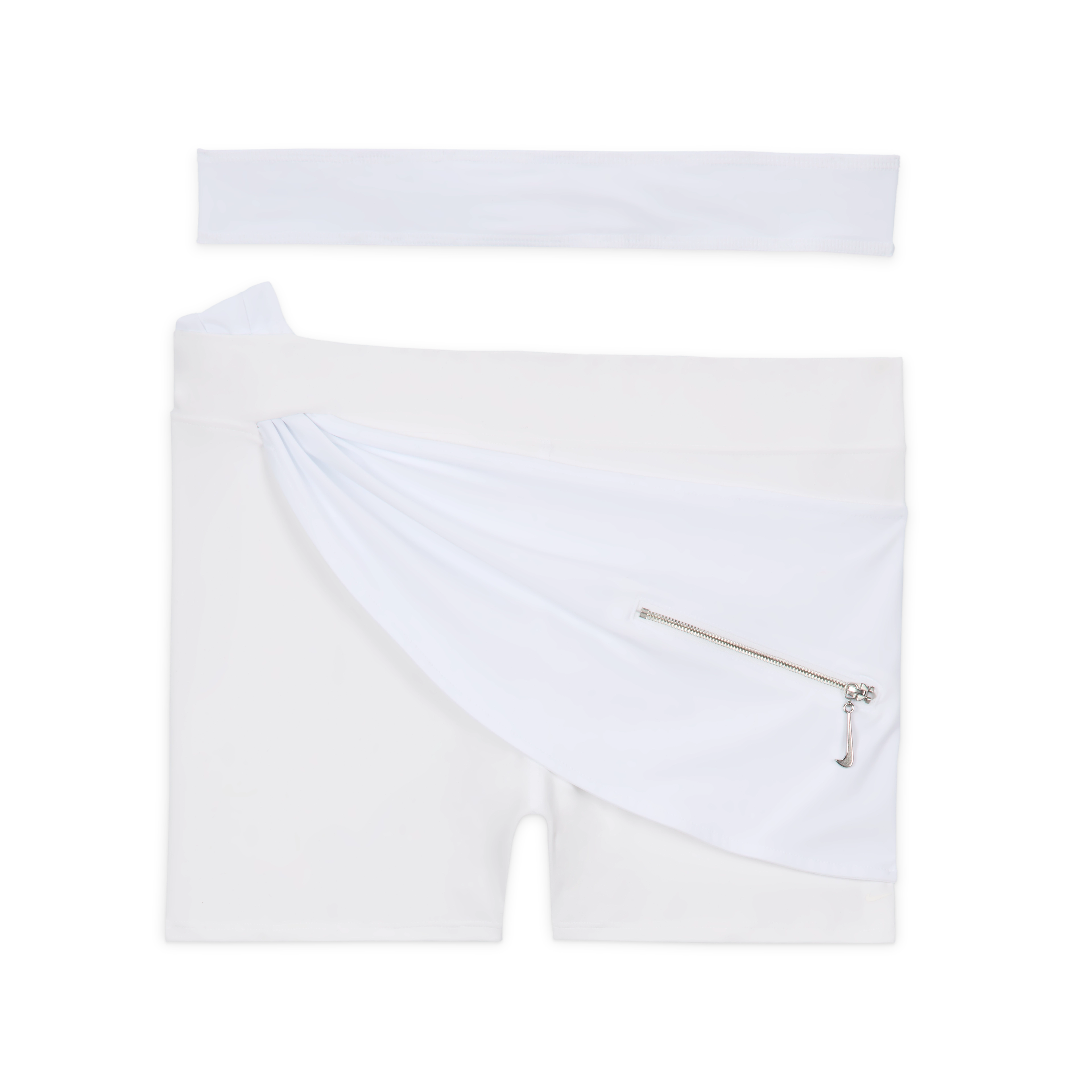 Overhead view of the Nike x Jacquemus Women's Layered Short in white. The short stretch shorts include wraparound material at the waist, which holds a small pocket with silver metal hardware and a zipper pull in the shape of a Swoosh. You see the white wraparound strap positioned above the shorts, which float on a black background.
