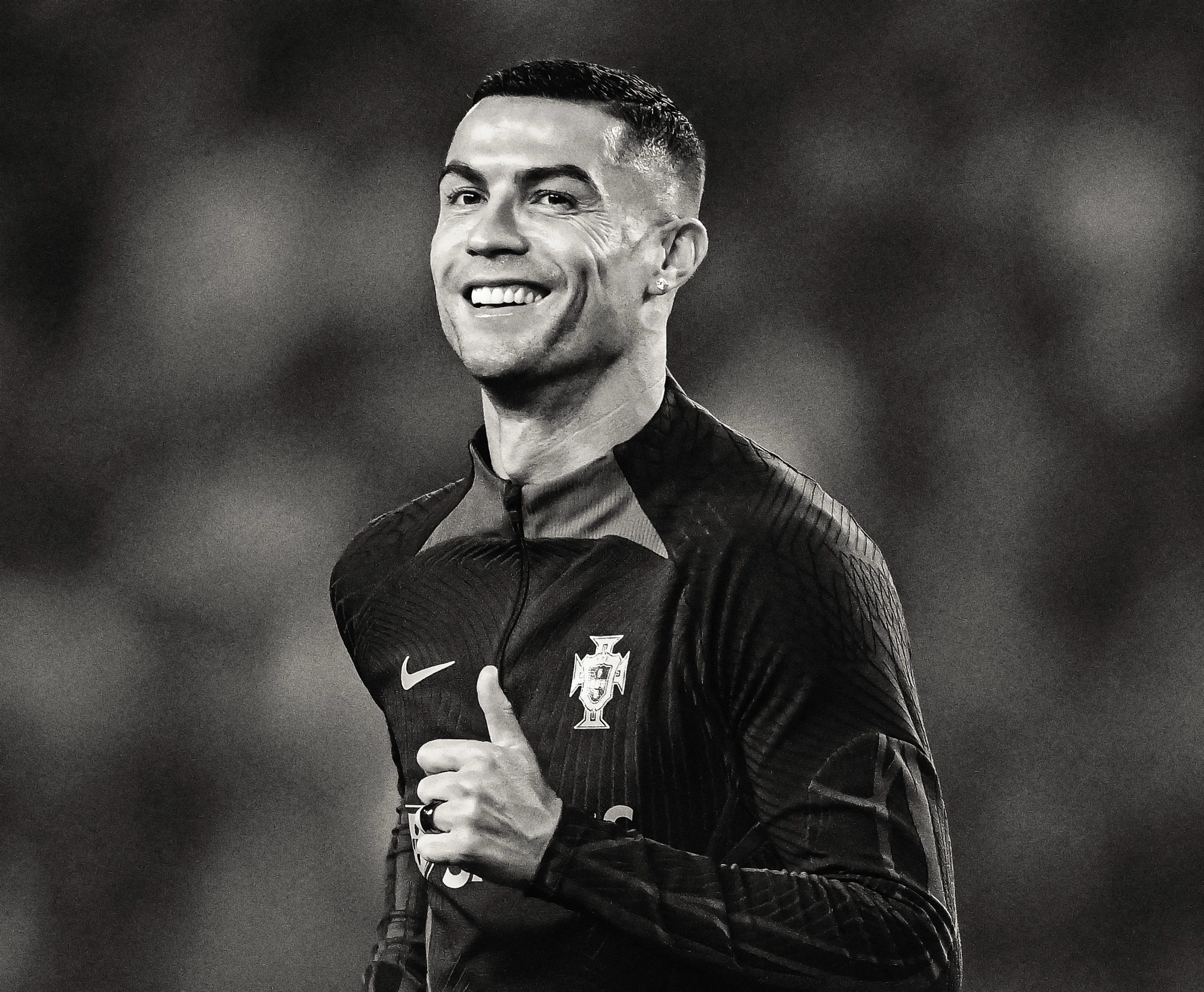 Black and white photo of Cristiano Ronaldo smiling and giving a thumbs up.