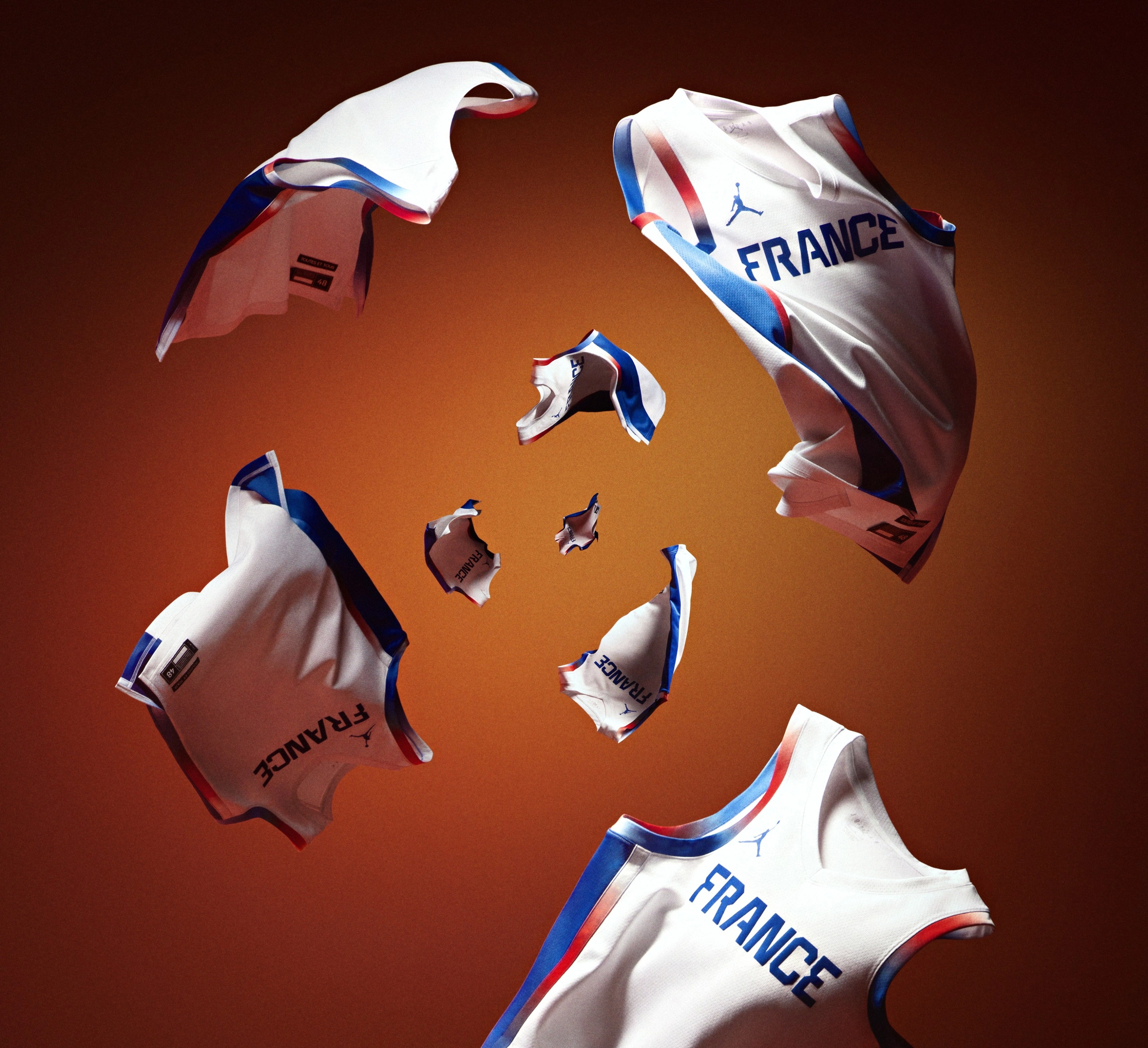 Several white France Basketball National Team Jerseys, featuring French flag themed trim, soar in a cyclone.