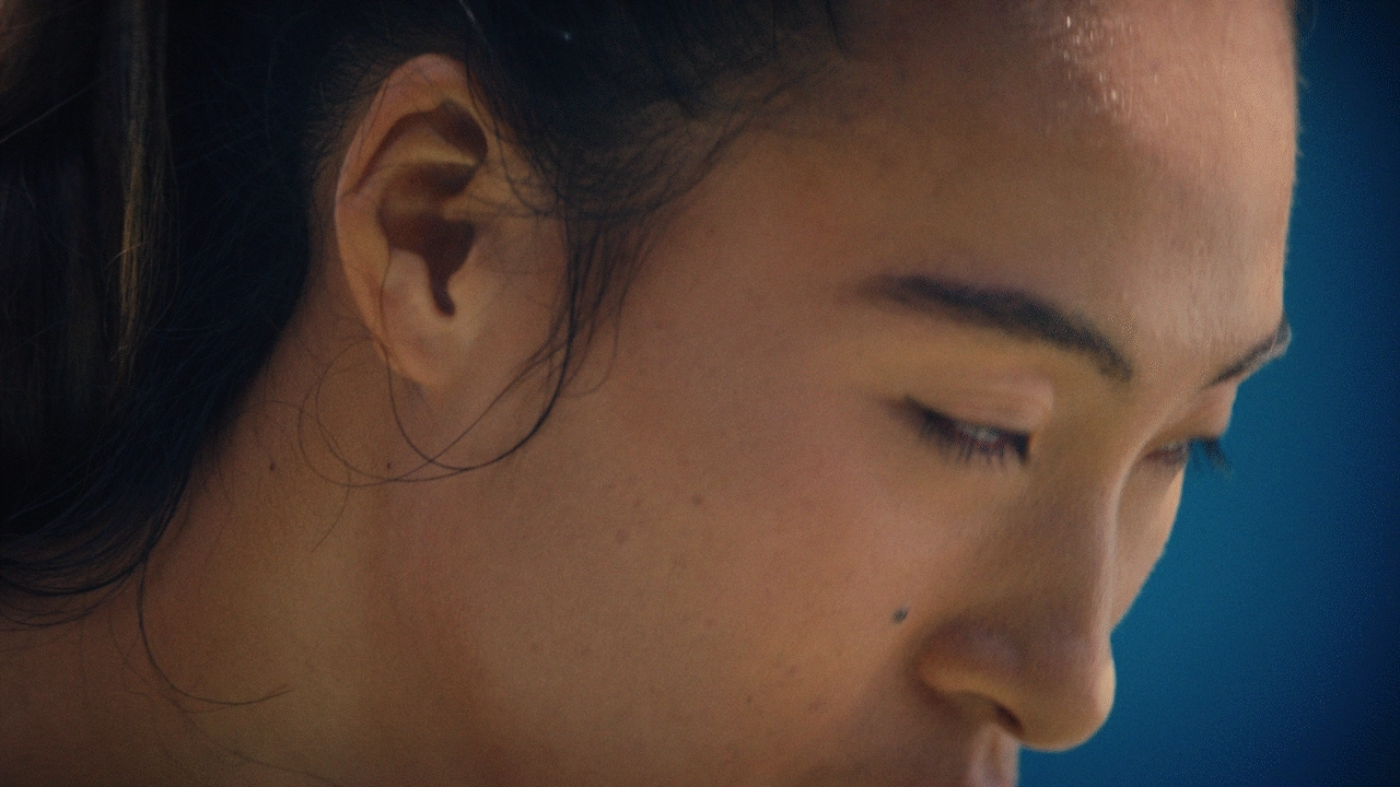 Video loop of Qinwen Zheng raising her eyes, potentially before a serve. Her face is framed on a blue background.