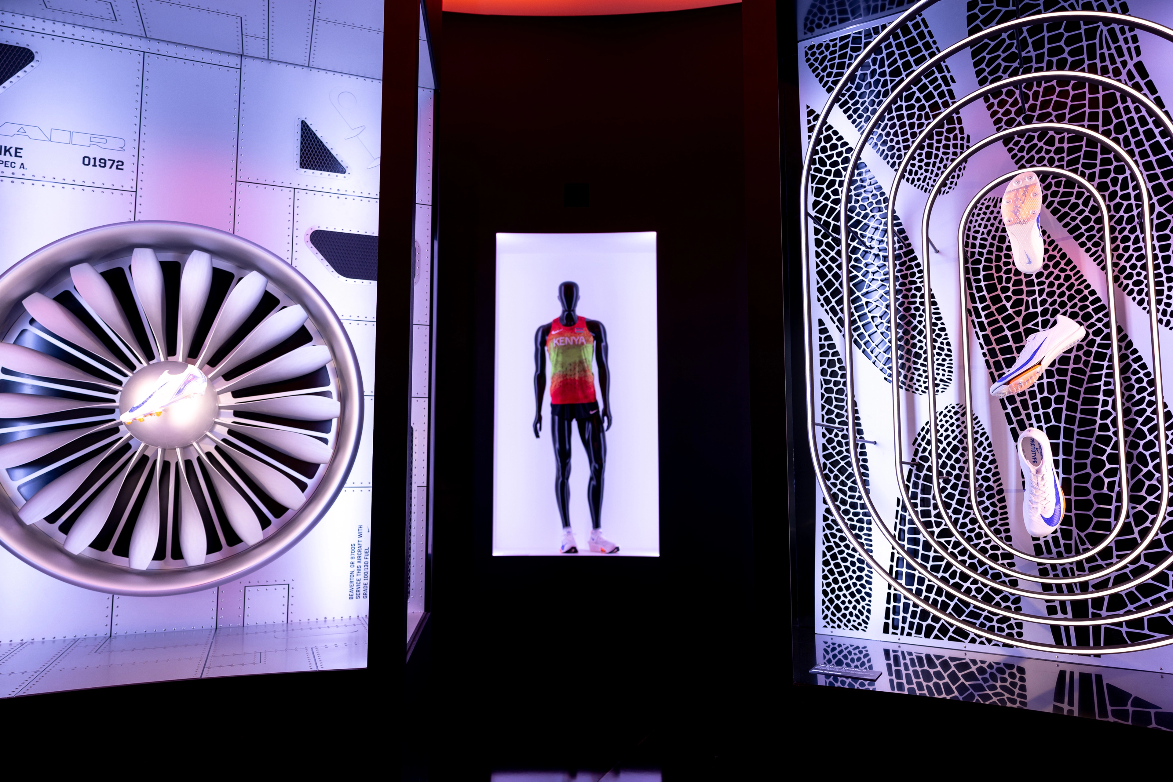 Three side by side artistic displays. On the left is a Nike Air sneaker centered inside of an airplane turbine, in the center is a mannequin wearing a jersey, and on the right are three Nike sneakers floating in front of a backdrop of artistically rendered shoe prints.