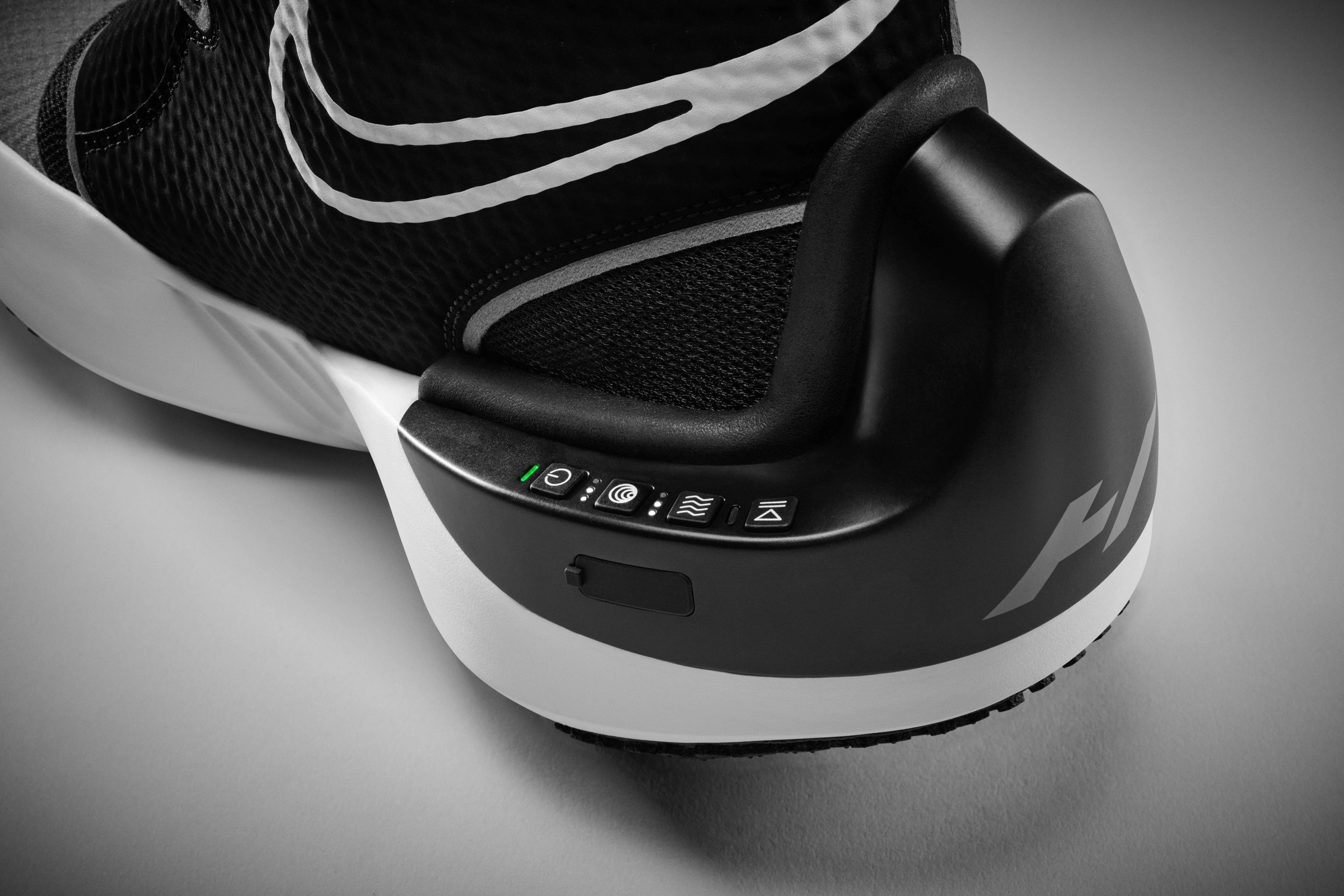 Detail view of Nike x Hyperice boot control features. 4 control buttons and charging port are integrated into the control feature of the boot.  Boot sits on a grey background.