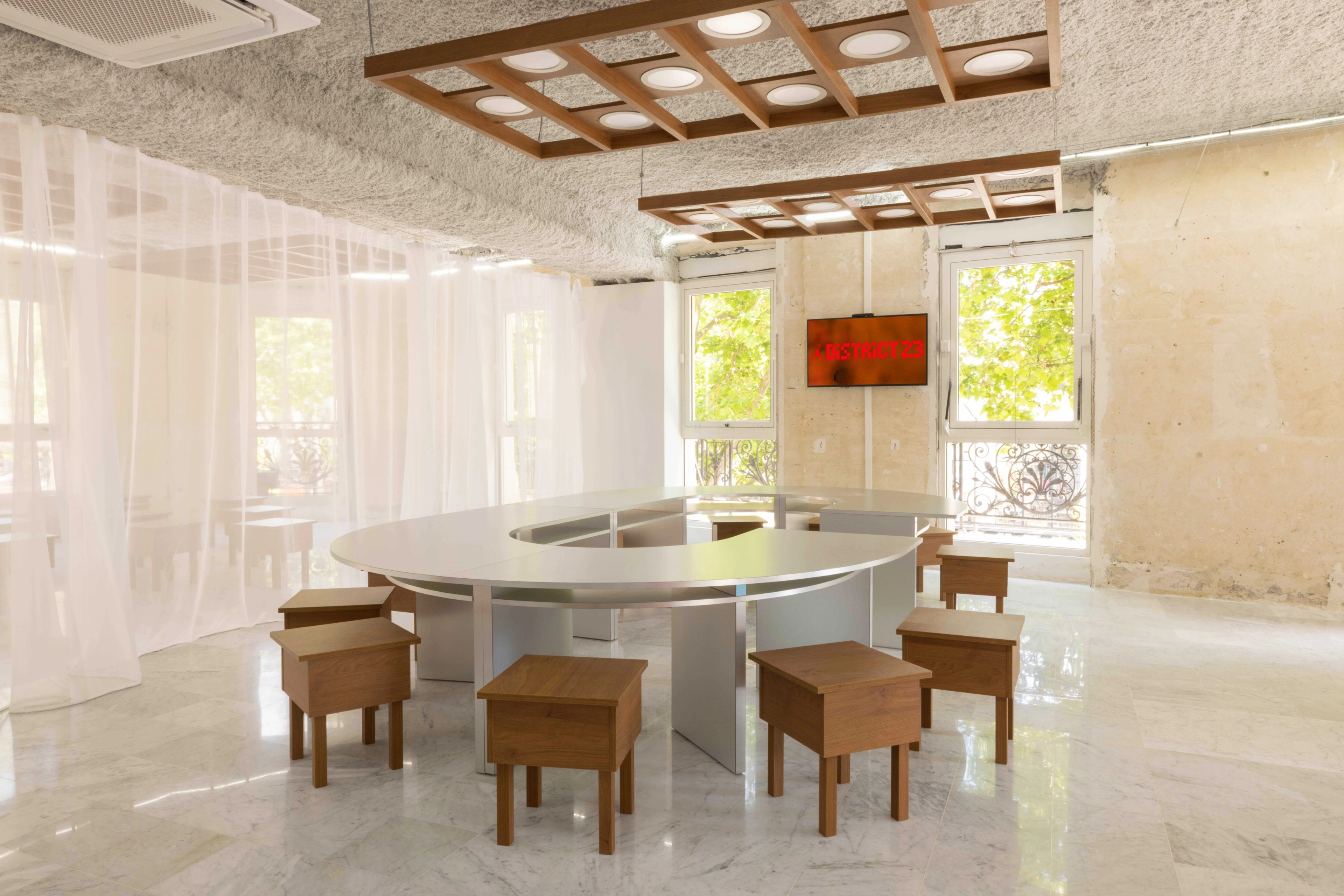 An oval shaped table with square wooden stools inside the District 23 workshop area.