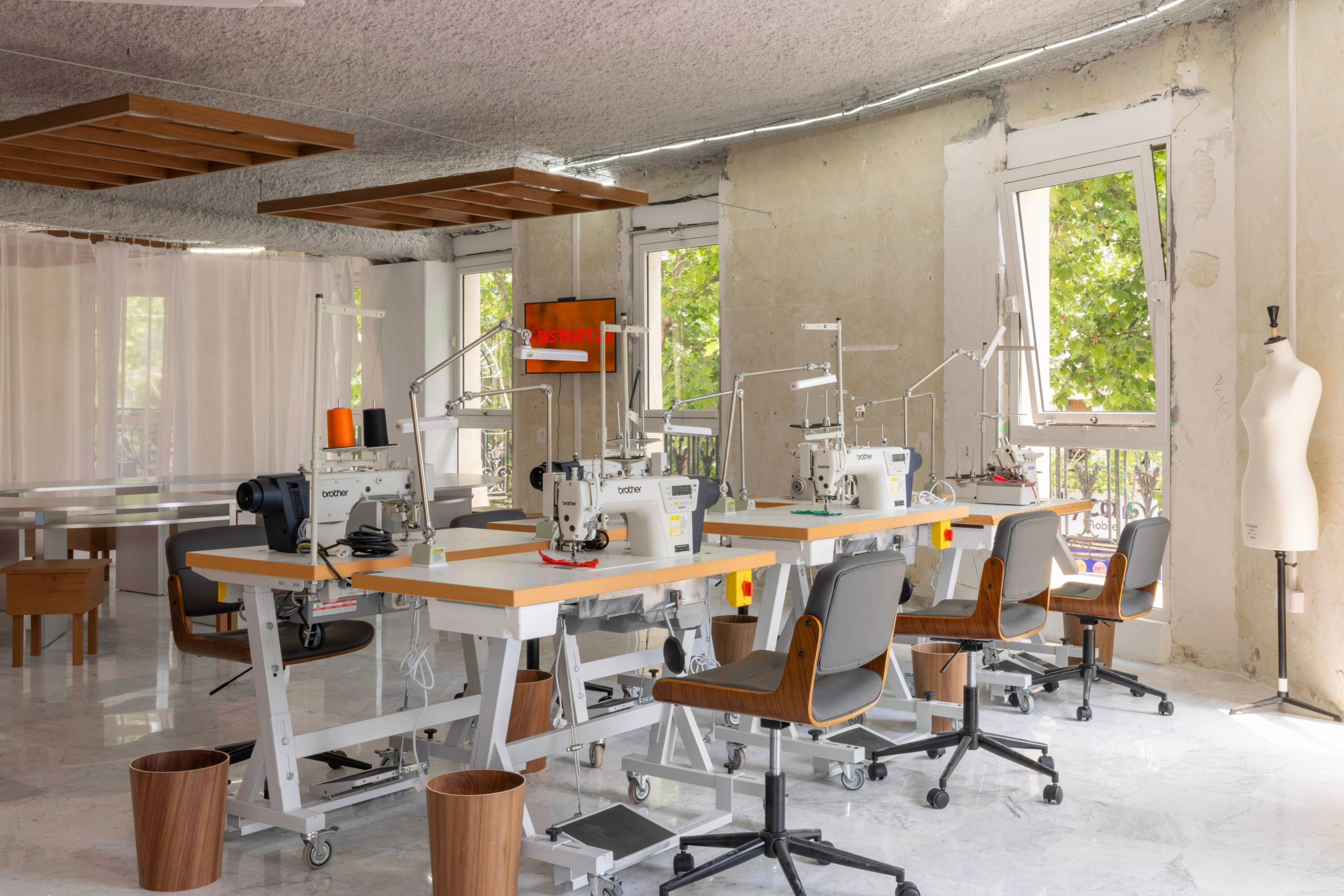 Six sewing tables and a sewing mannequin inside the District 23 workshop area.