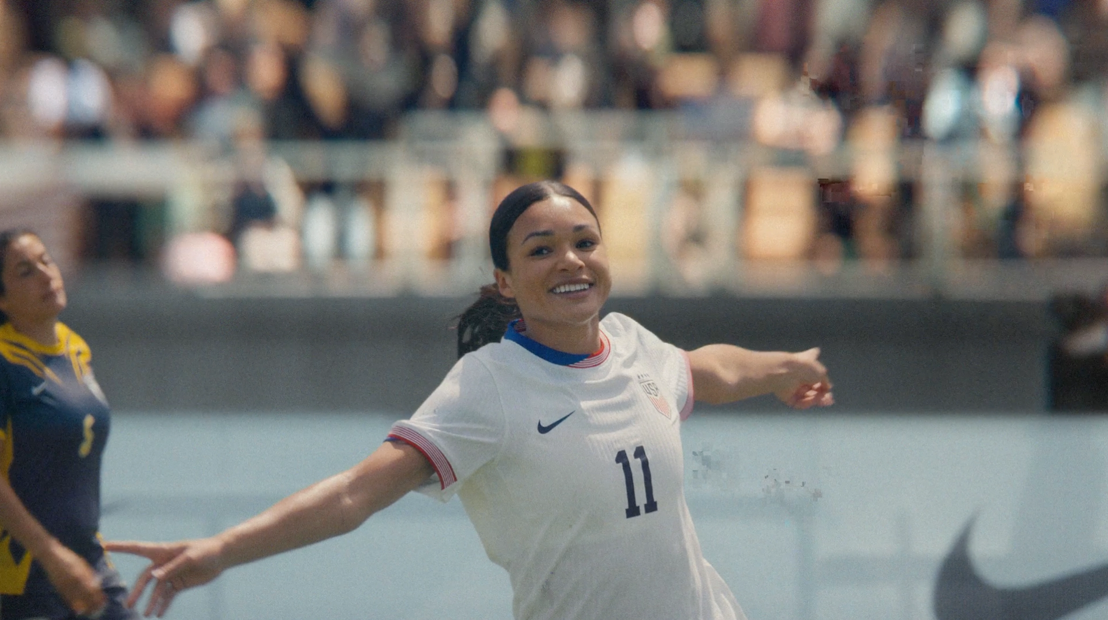 Sophia Smith wears her white Team USA football jersey, showing 11, and celebrates with arms wide after a goal.