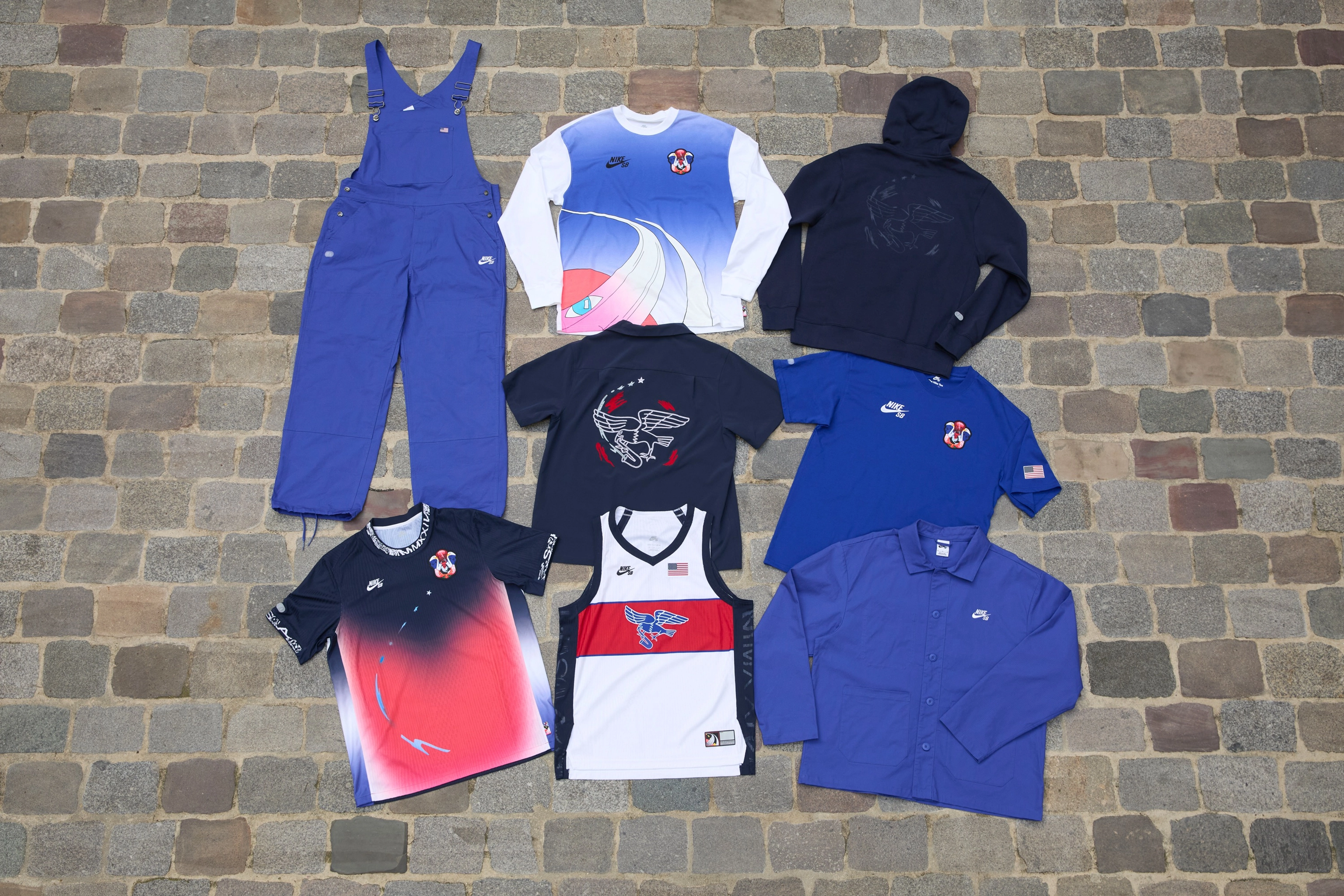 Overhead view of seven pieces of clothing items from the skateboarding federation kits for the USA olympic team.