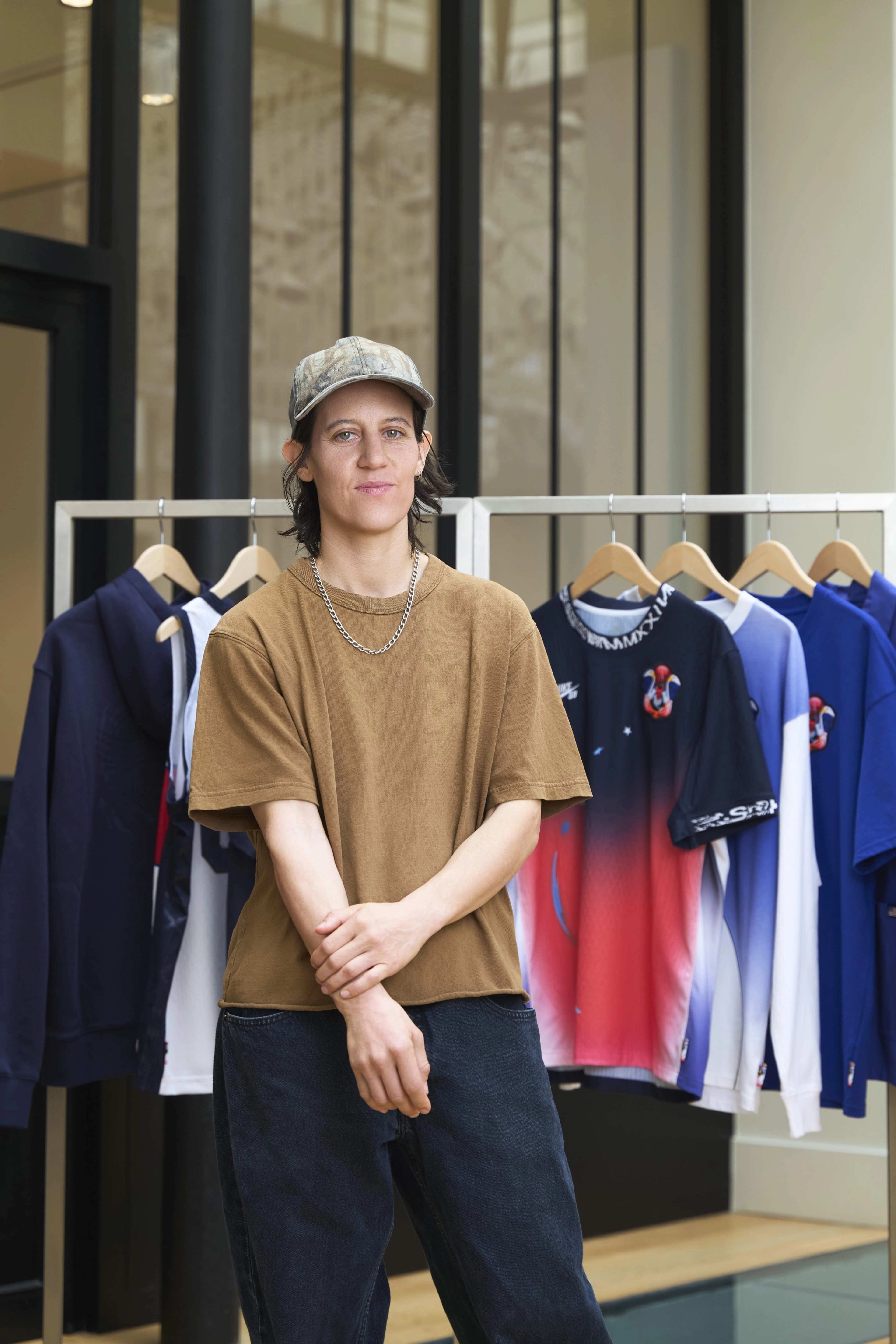 Converse CONS team rider Alexis Sable posing in front of a rack of the USA skateboarding federation kit clothes.