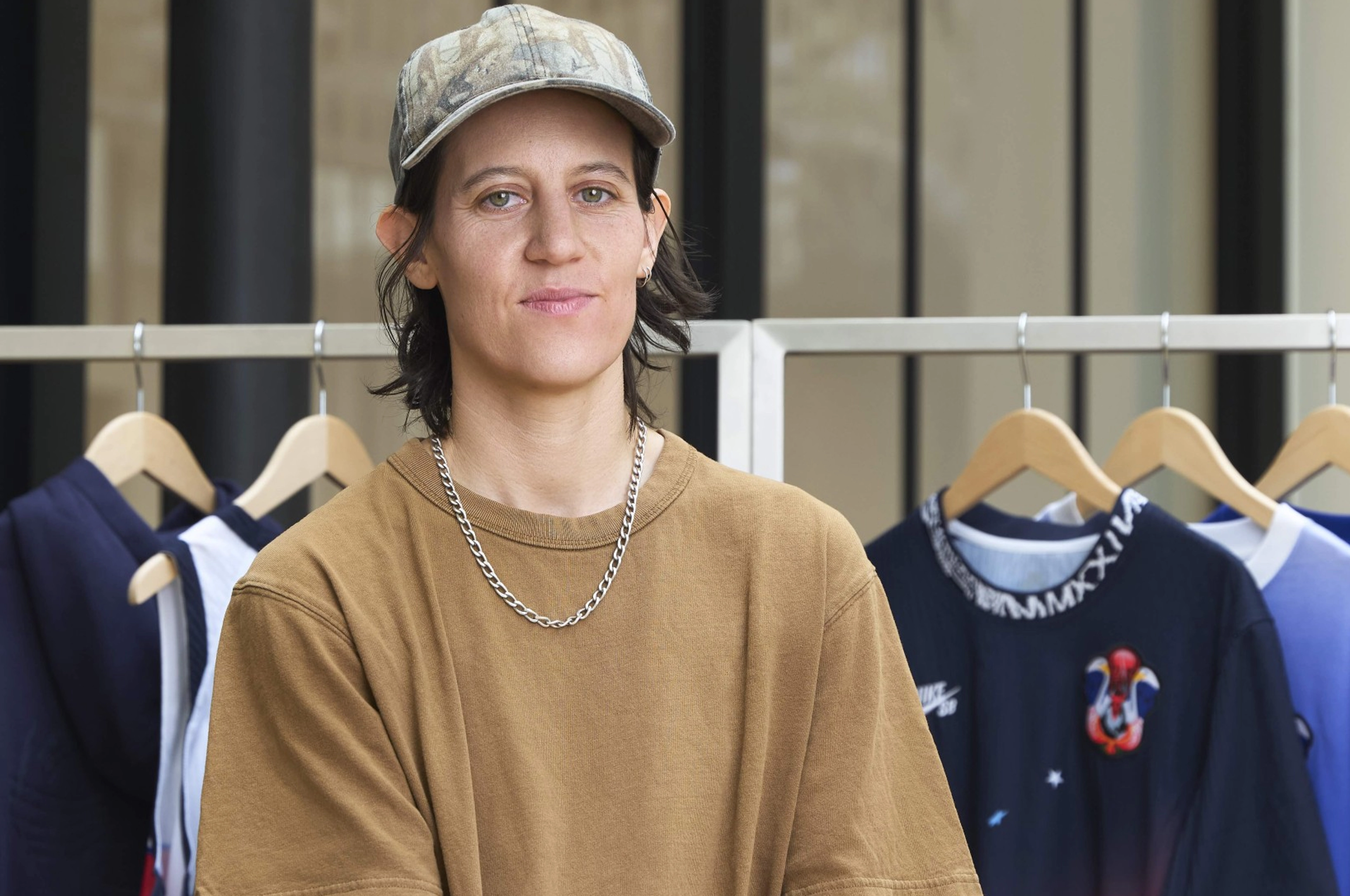 Converse CONS team rider Alexis Sable posing in front of a rack of the USA skateboarding federation kit clothes.