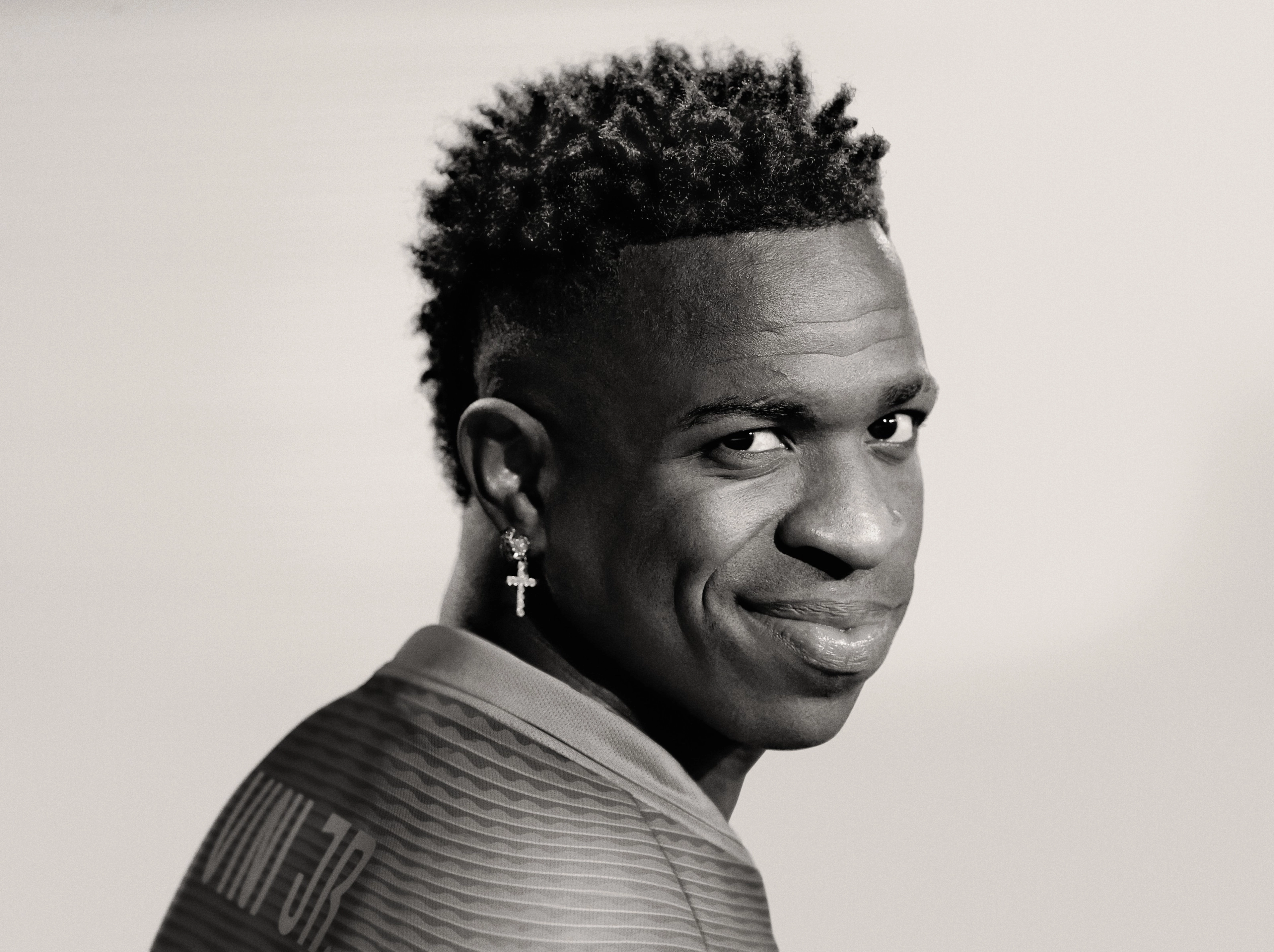 Black and white photo of Vini Jr. smiling while looking over his shoulder.
