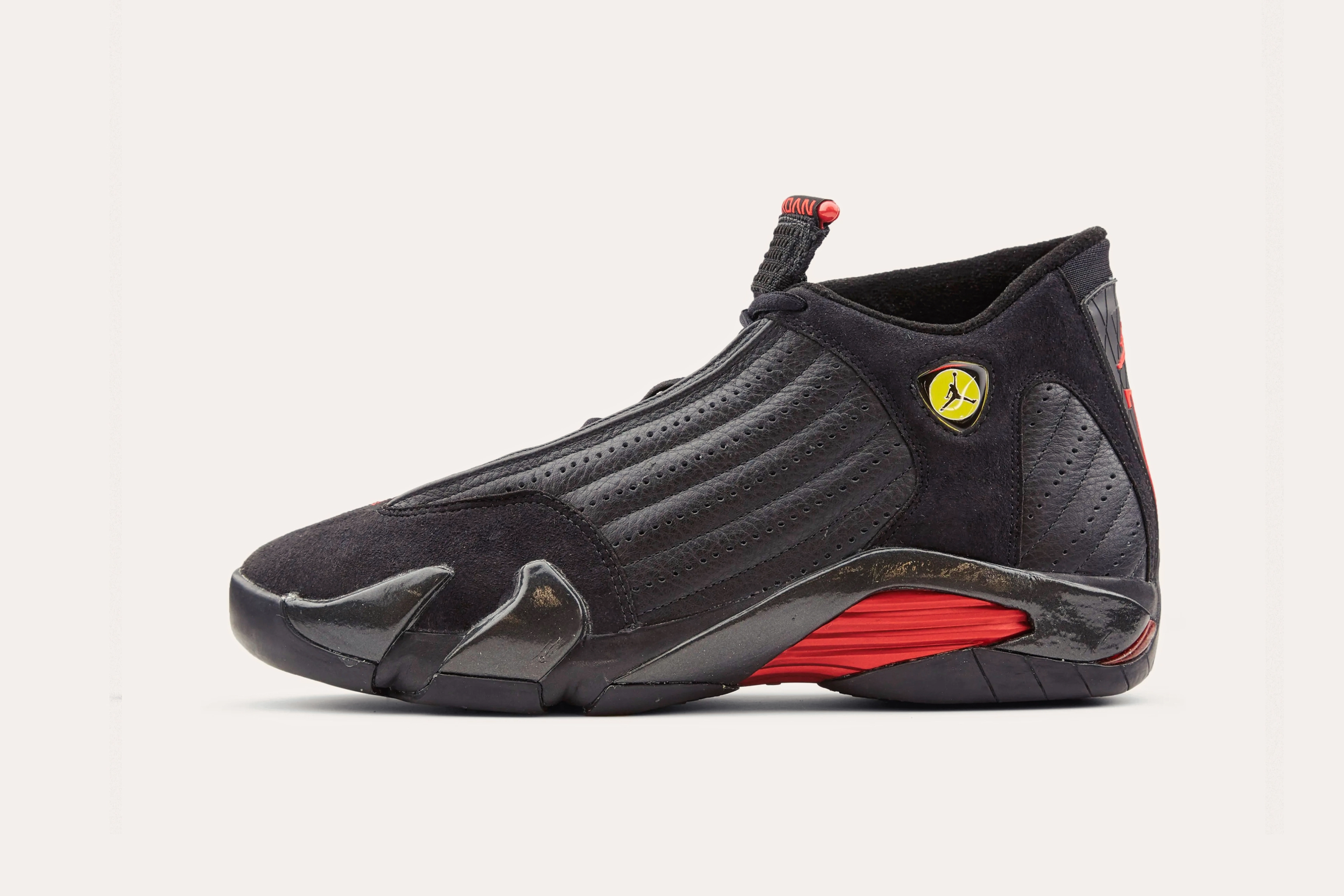 A black Nike sneaker with an Air Jordan emblem on the side of the cuff and a red arch in the sole.