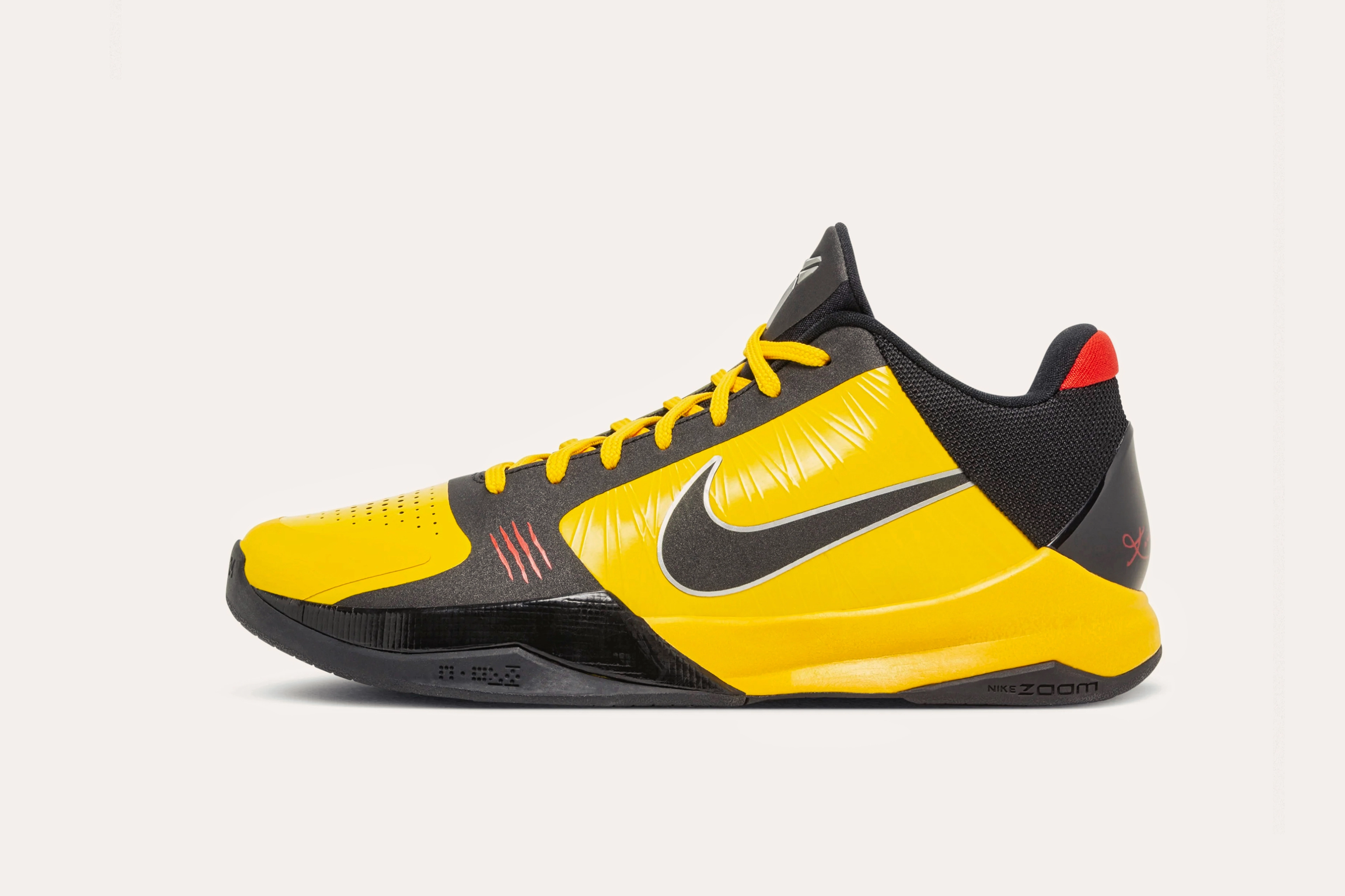 A dark grey sneaker with yellow laces, a yellow toecap, yellow siding with a dark grey Nike swoosh, and a red rear cuff.