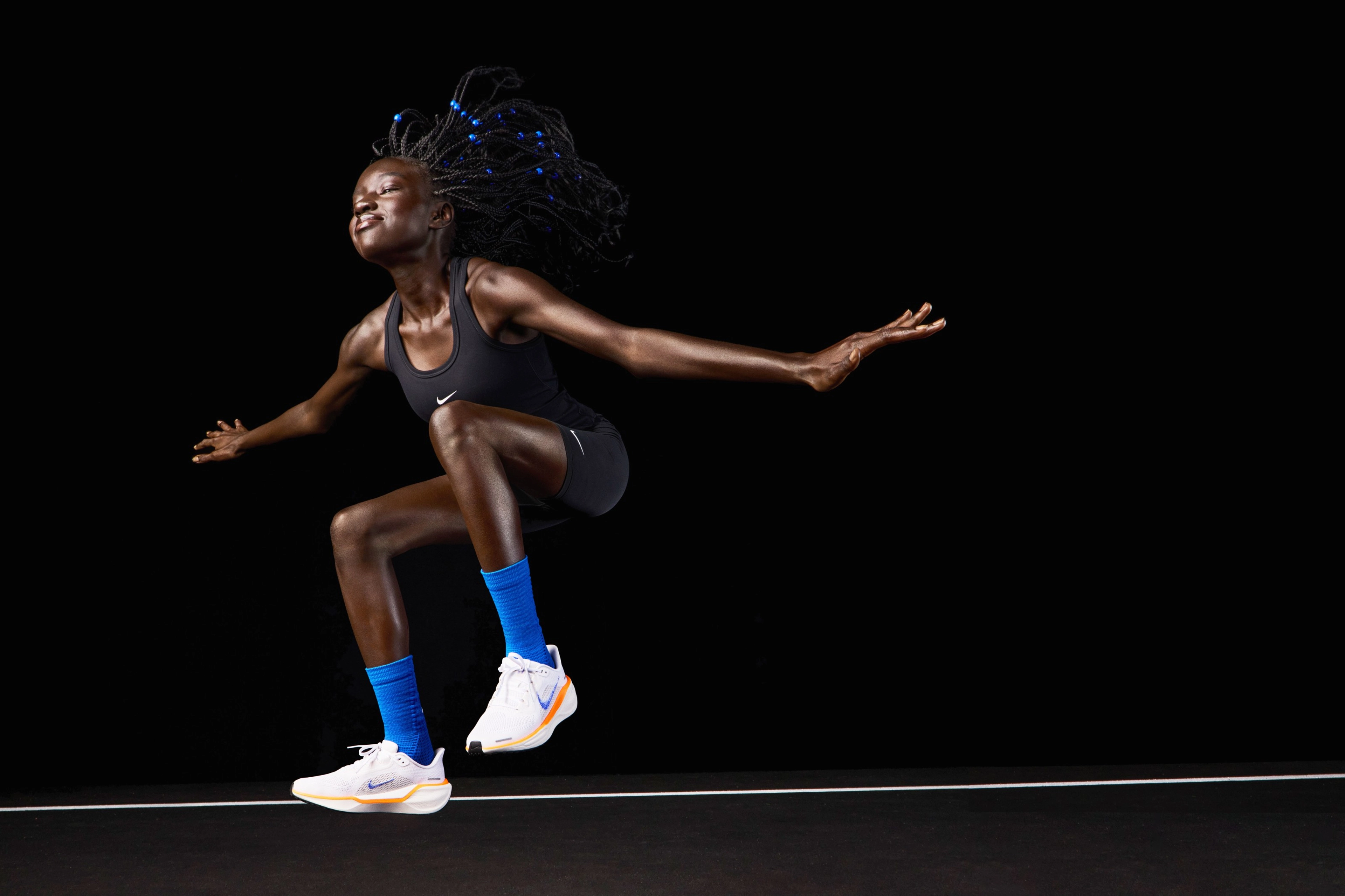 American 800 meter runner Akouc Chany wearing the Nike Pegasus 41 while jumping in air with her hands outstretched and her eyes closed.