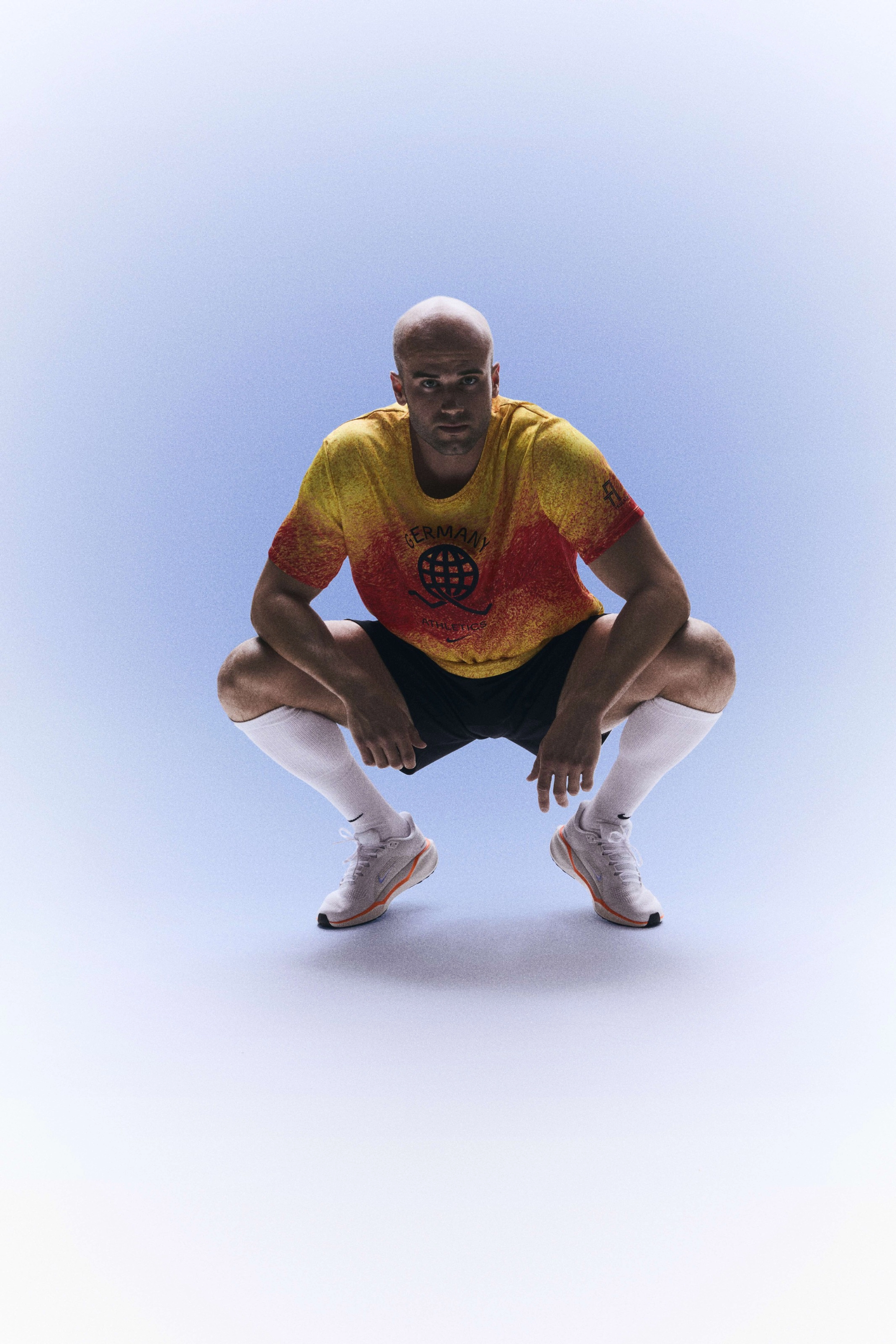 Julian Weber in a squatting position while wearing his Germany track and field kit uniform.