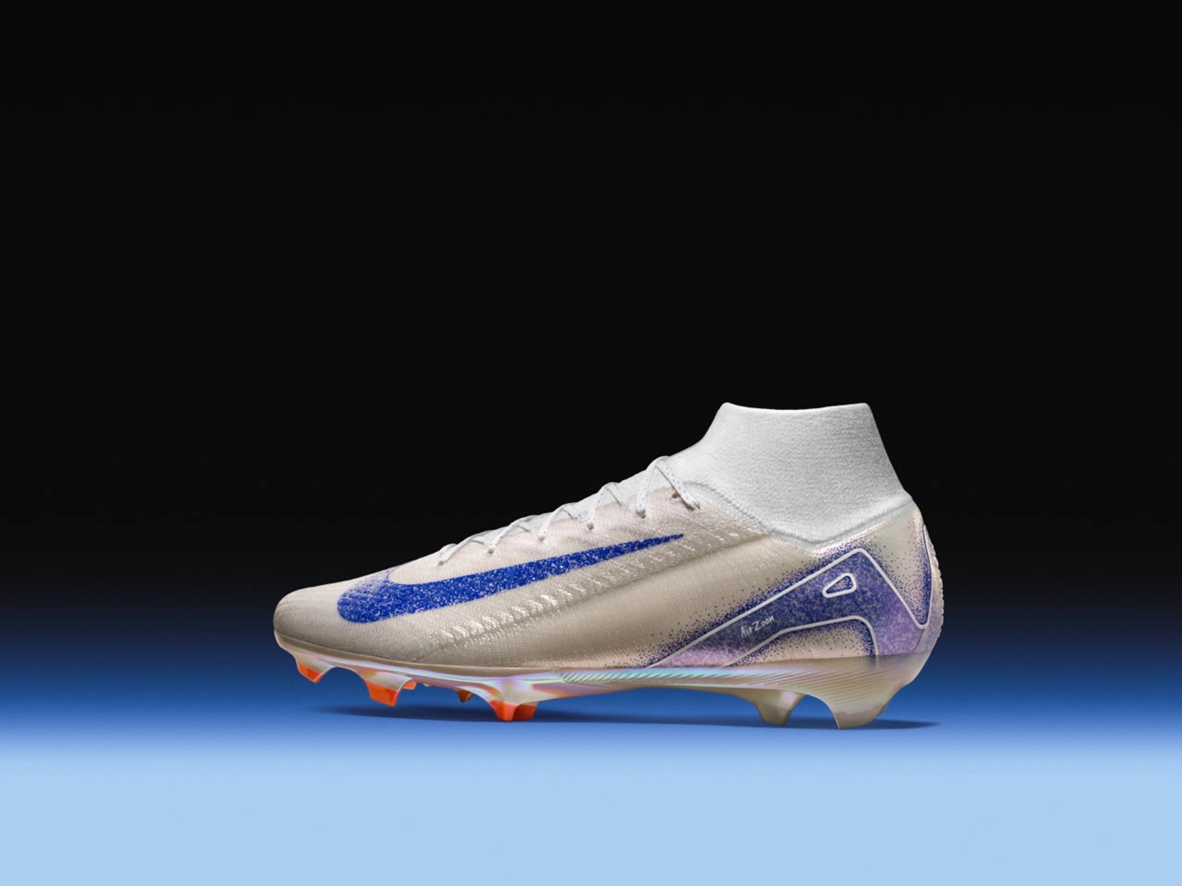 Left side view of Nike Air Zoom Mercurial Superfly football boot in the Blueprint colorway. White upper with a speckled blue Swoosh, orange Air Zoom unit, and iridescent yellow orange sole plate. The boot sits on a blue floor against a black background.