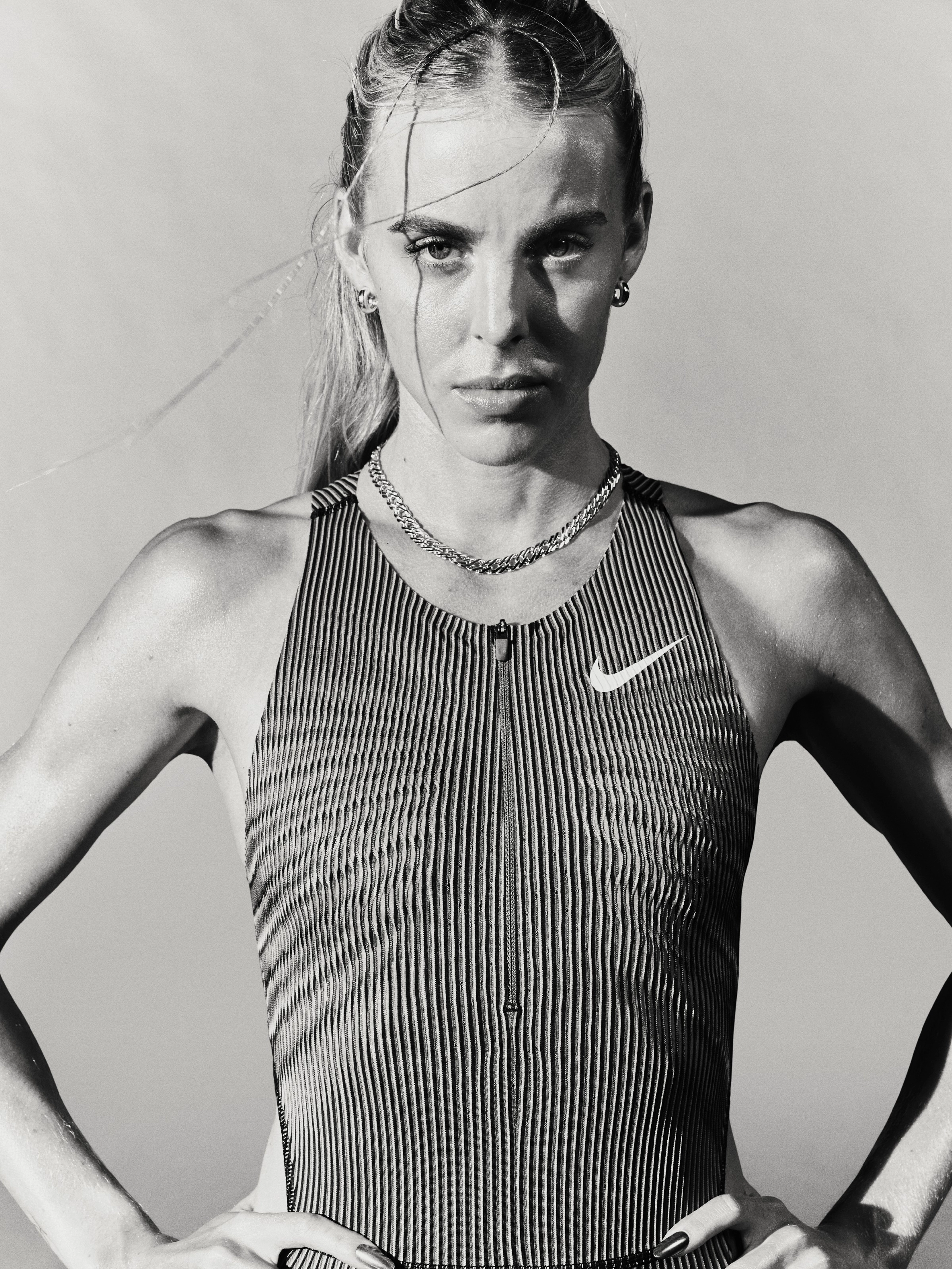 Black and white photo of Keely Hodgkinson, wearing a Nike runnining tank and holding her hands on her hips.