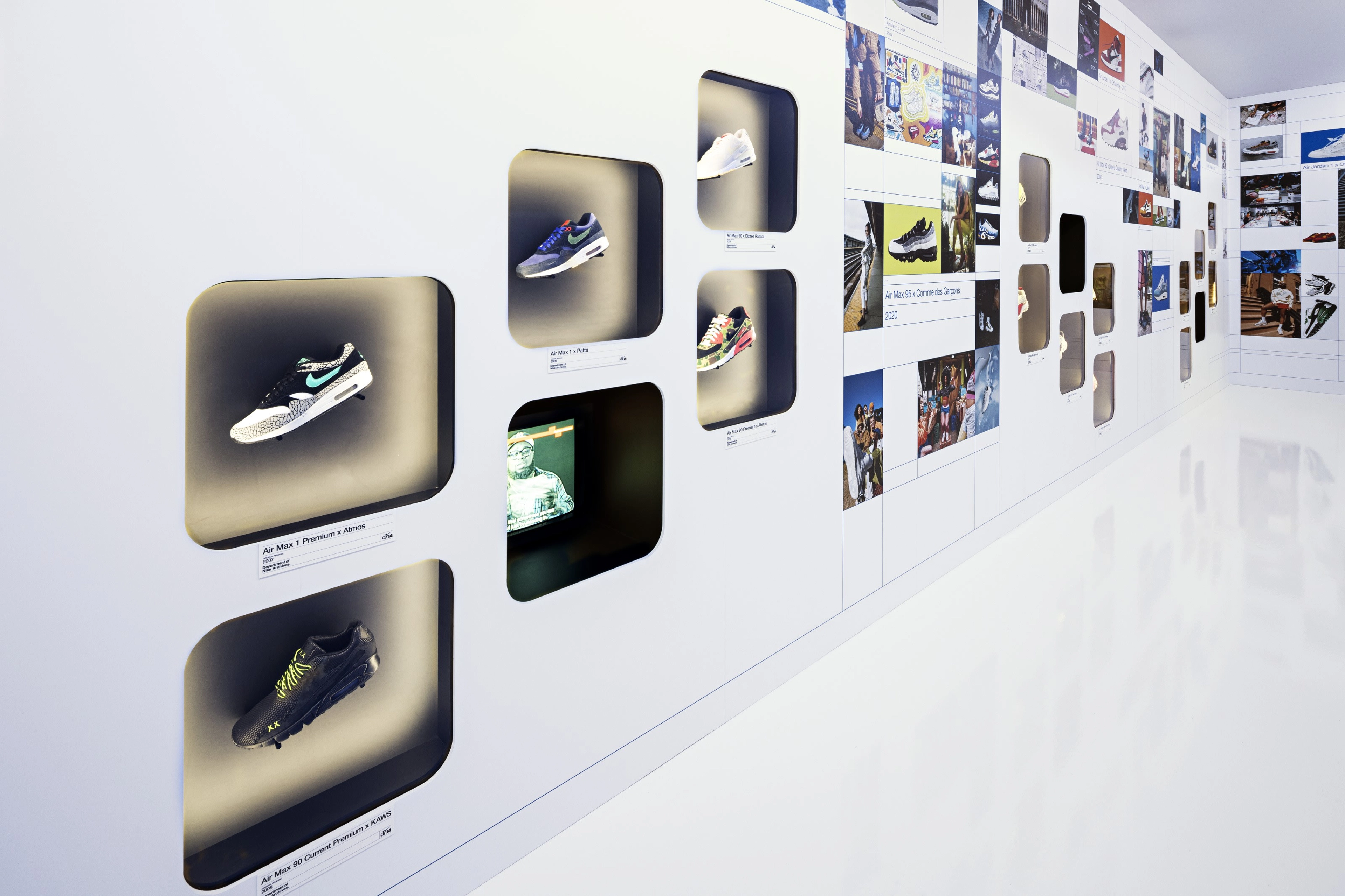 Several Nike sneakers are displayed in a cascading pattern on a white wall featuring many large photos.