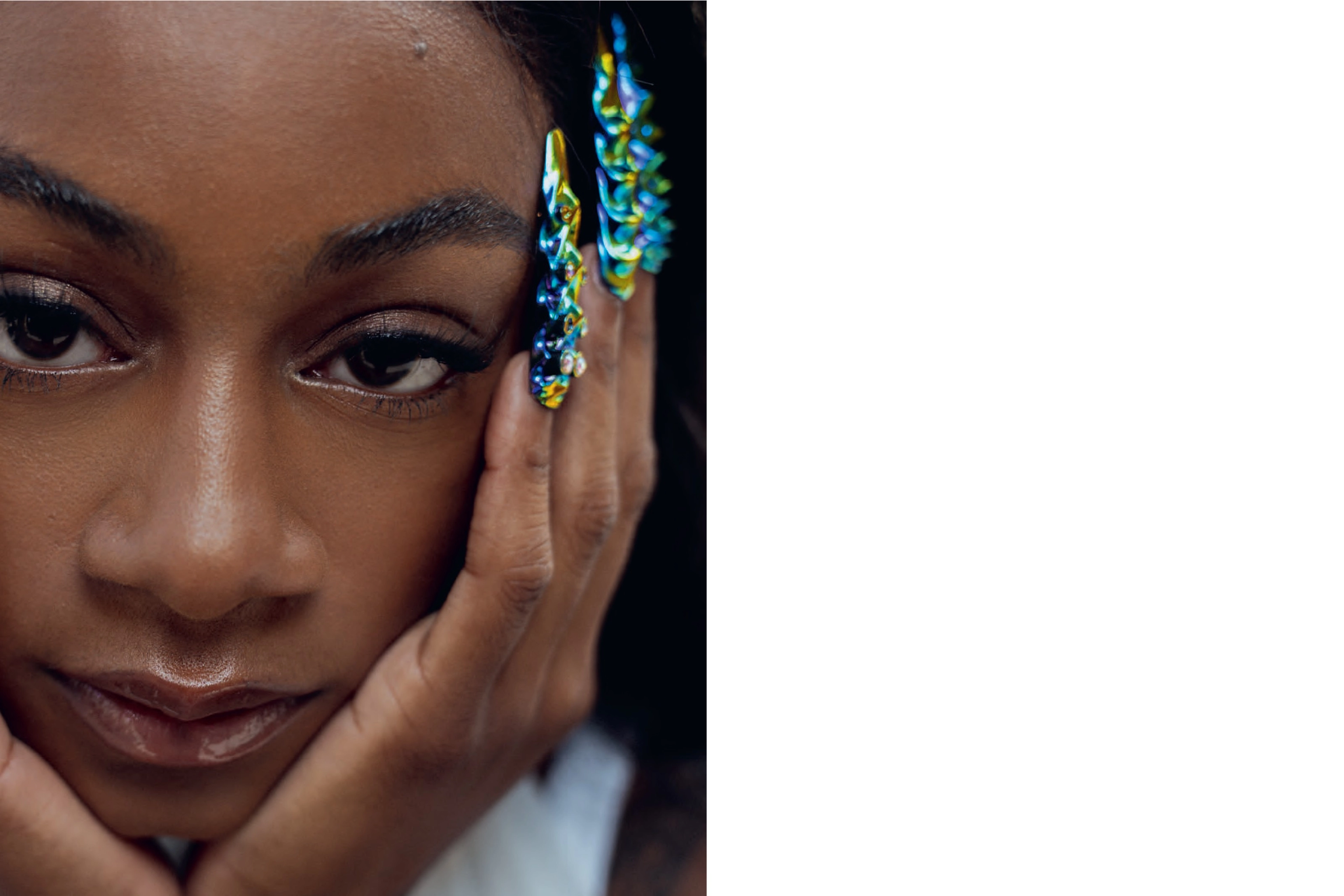 Close up portrait of ShaCarri Richardson looking directly at the camera. She holds her face in her hands, and we see her colorful nail art displayed.
