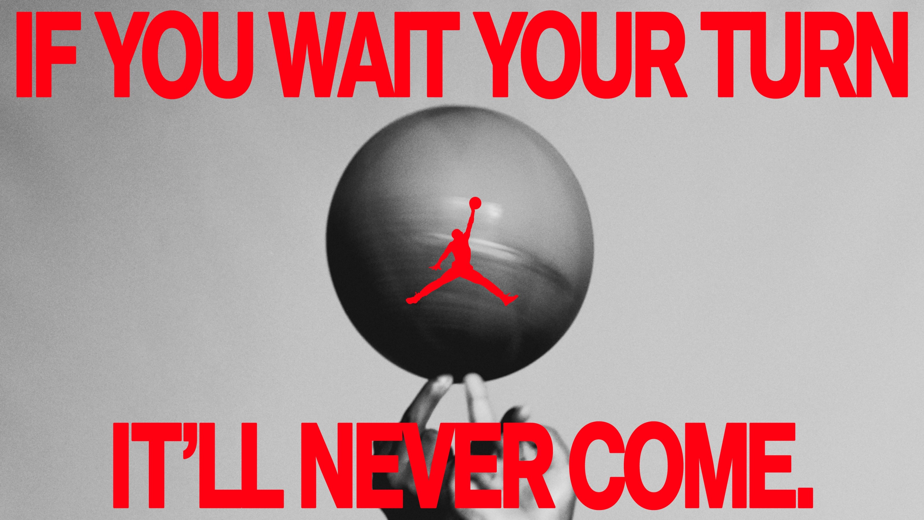 Black and white photo of a pair of hands twirling a basketball. A red caption reads, "If you wait your turn it'll never come." The Air Jordan logo is in the center.