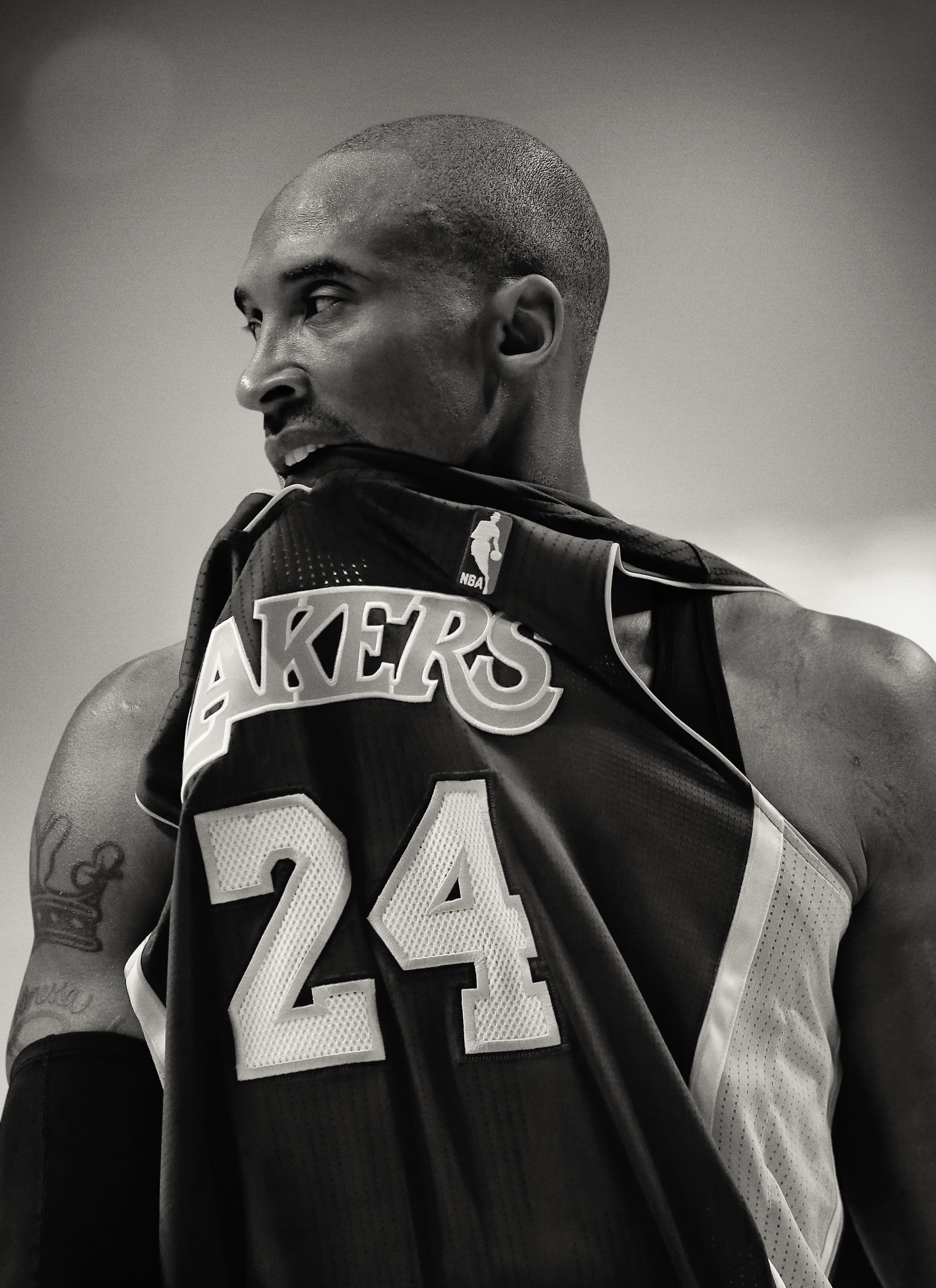 Black and white photo of Kobe Bryant biting the front collar of his jersey.