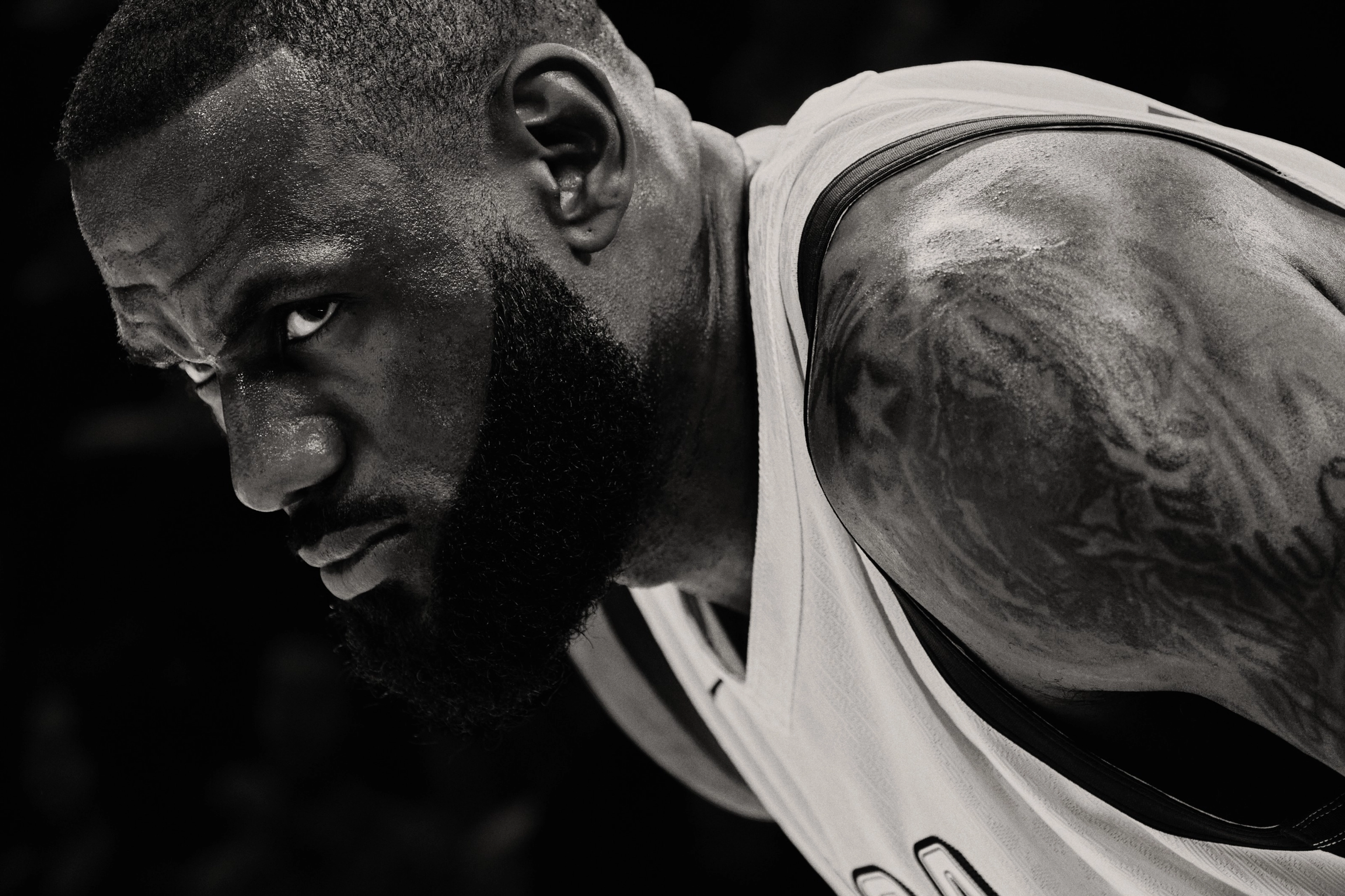 Black and white close up of Lebron James in a white Team USA jersey. Lebron is bent over with is eyes looking over to a competitor, ready for action.