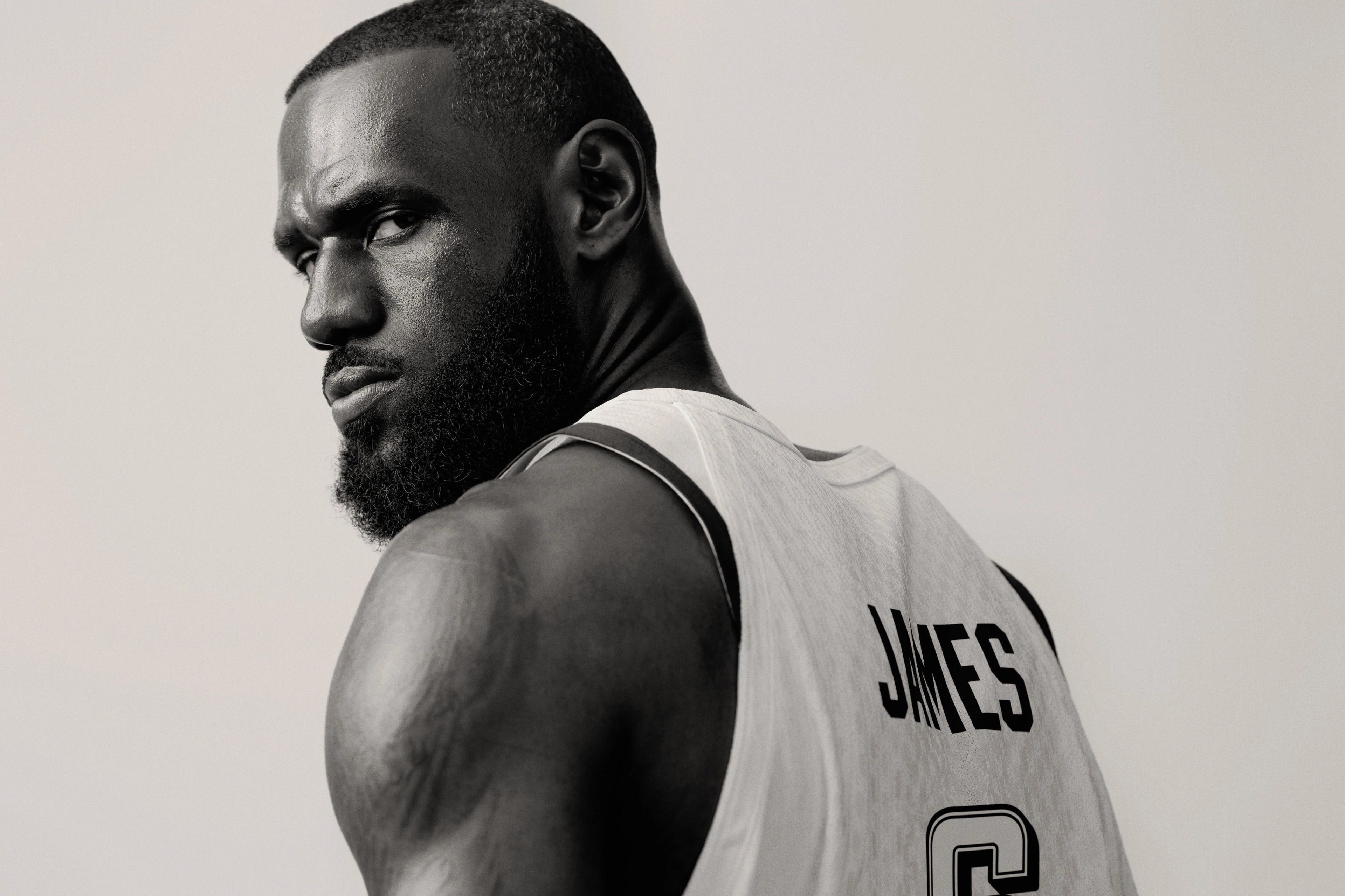 Black and white close up of Lebron James looking back over his shoulder at the camer. He wears his Team USA jersey with James appearing on the back.