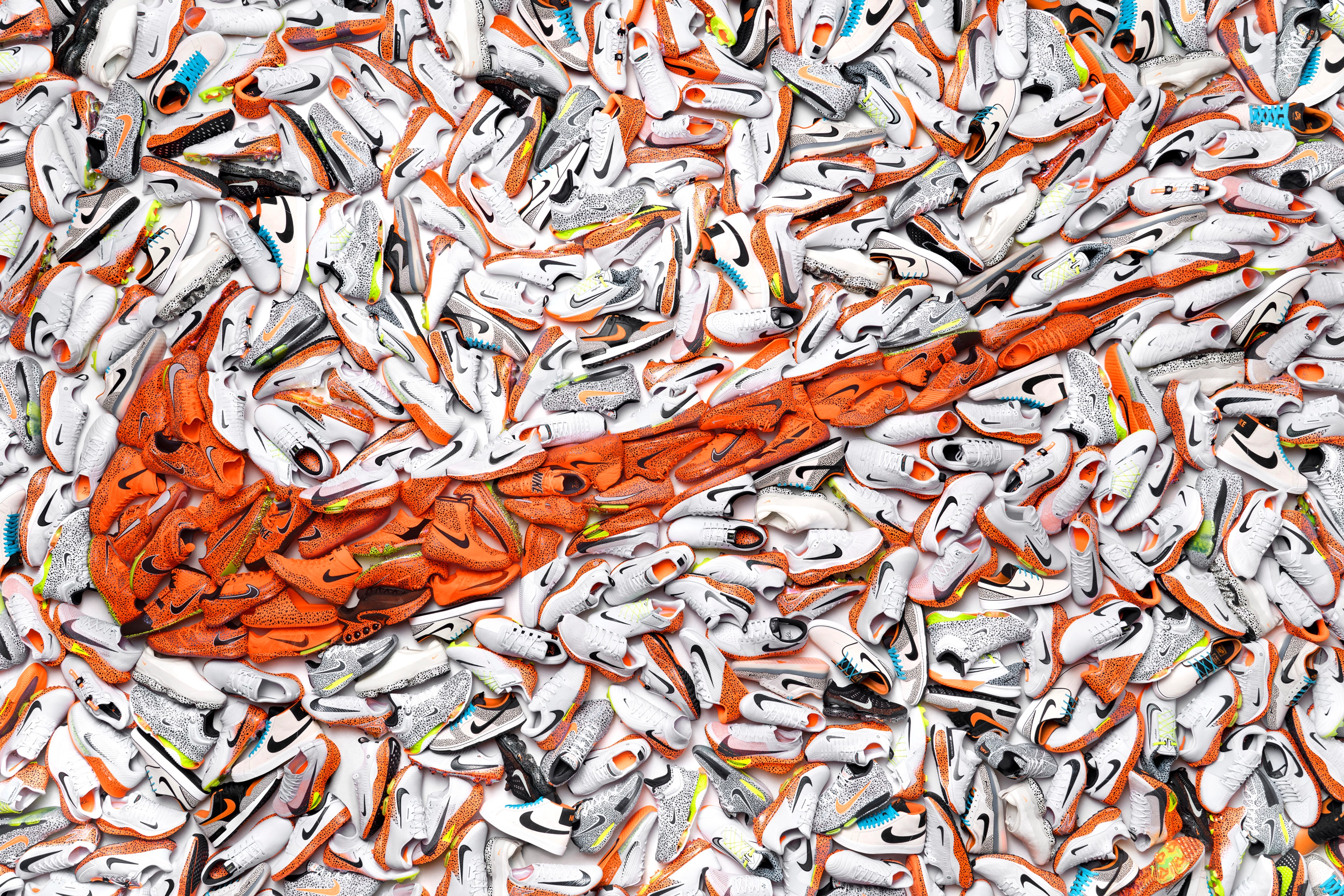 Mosaic of 55 different shoes from the Nike Electric Pack, strategically placed so the Electric colorway, orange with a blue/black speckled print, creates a bold orange Nike Swoosh.