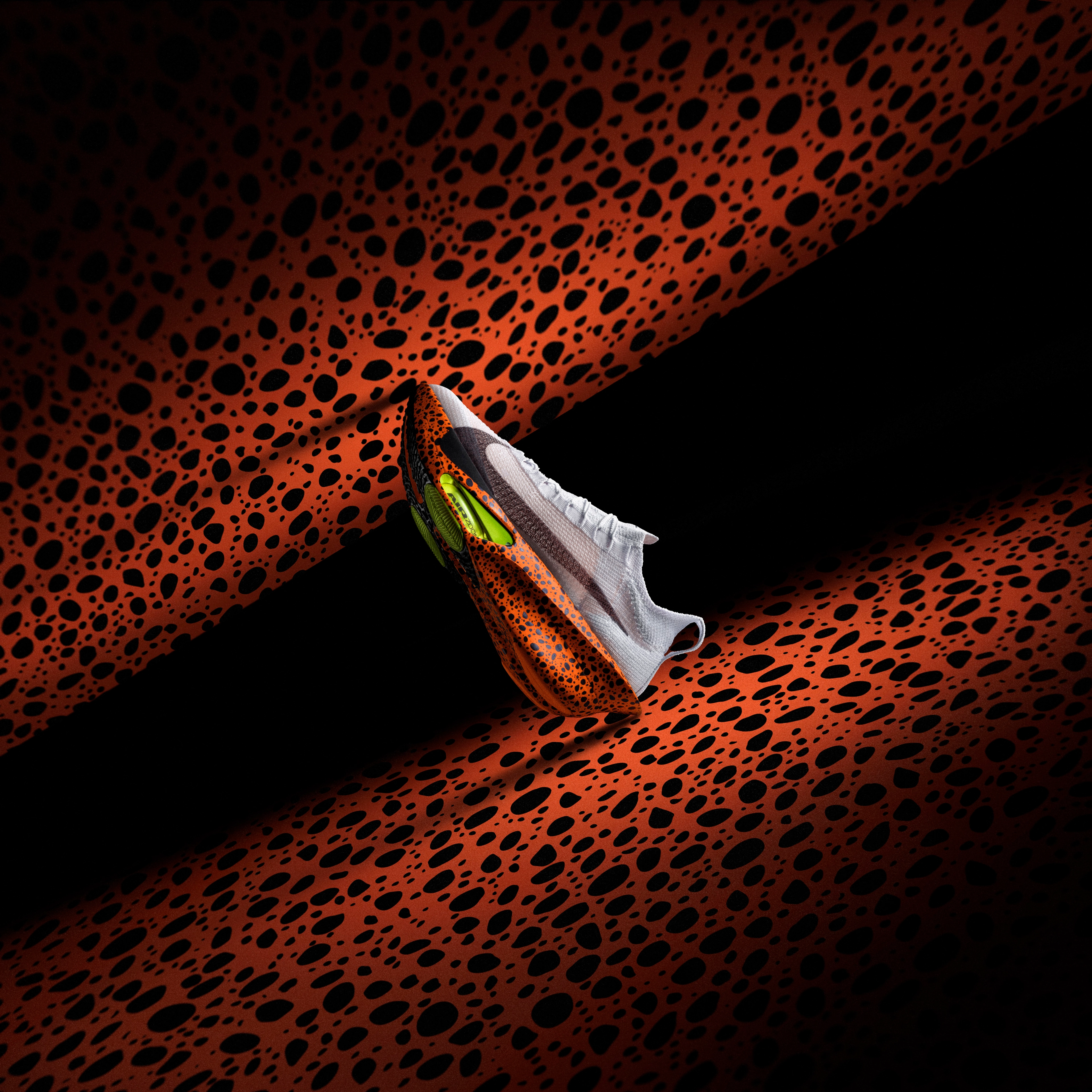 Side view of the Nike Alphafly 3 running shoe in the Electric colorway, which is a white upper with a speckled blue/black pattern on the midsole, black Swoosh, and volt Air Zoom units on the forefoot. The shoe sits on an orange Electric pattern background.