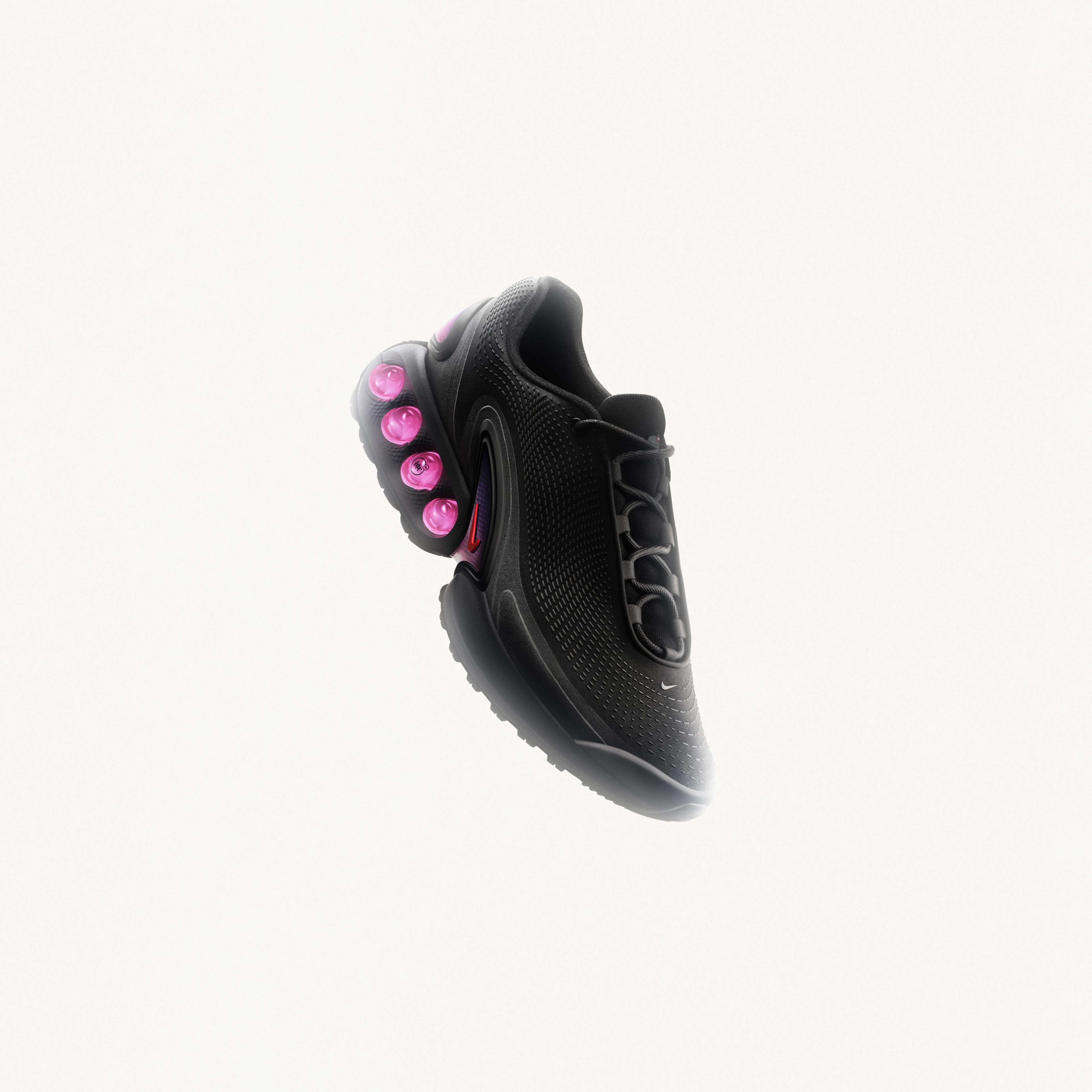 Front angled view of the Nike Air Max Dn in black with light crimson dynamic air unit systems comprised of a dual chamber with four tubes