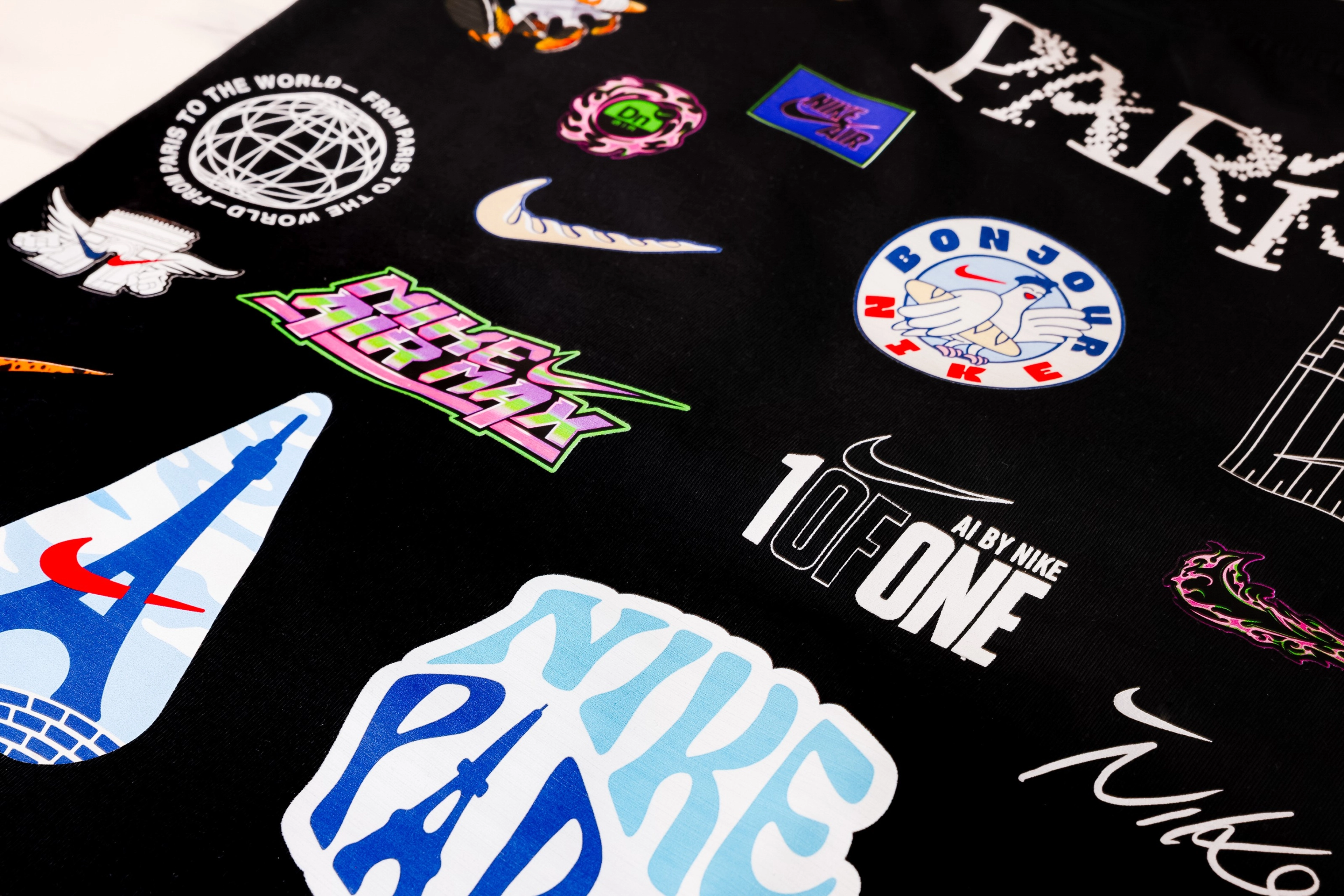 Situated on top of a black background, we see a spectrum of example of the AI-generated designs athletes can create and use to customize Nike apparel. The designs include customized Swooshes, the word PARIS, and Nike logos.