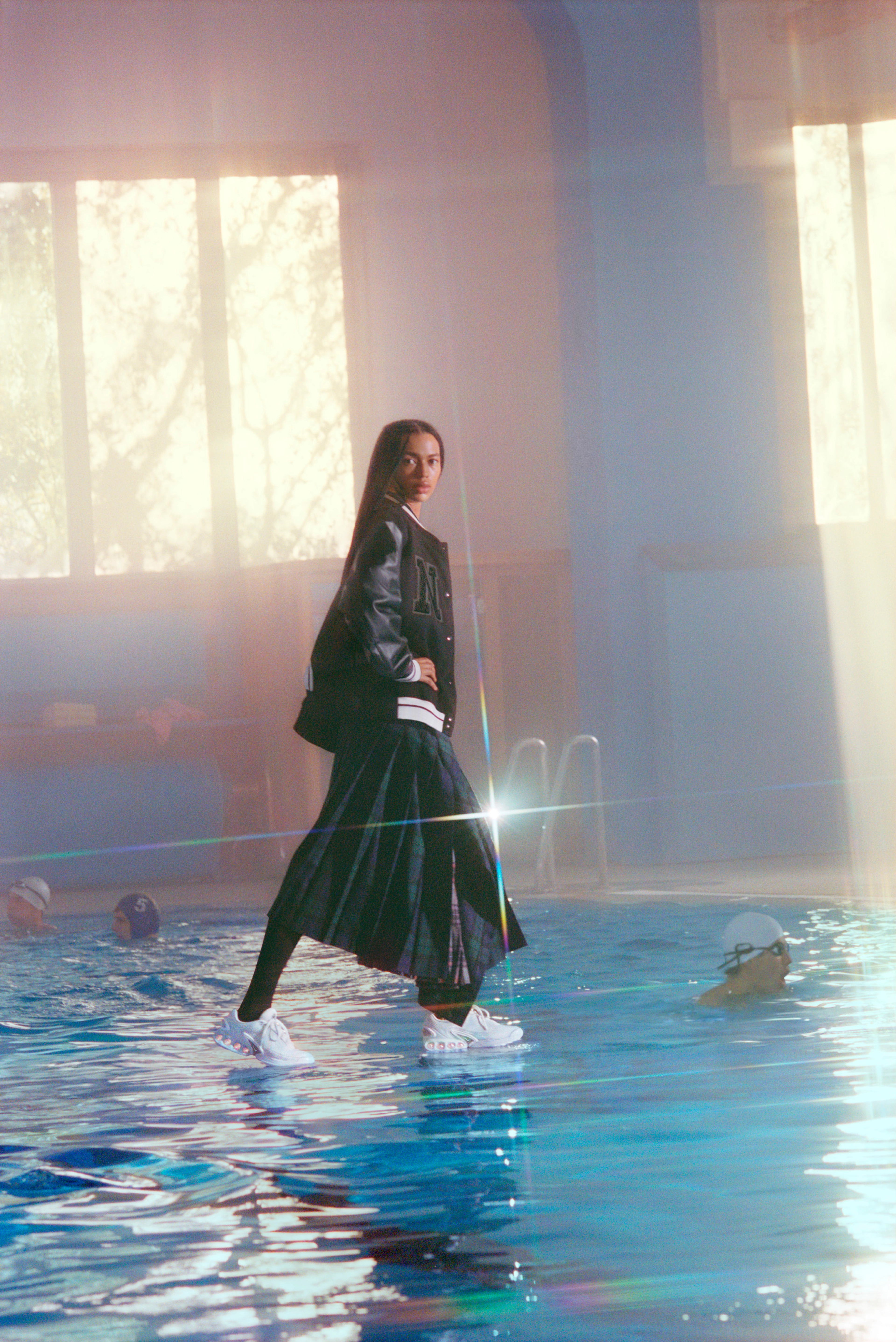 Full view of a female model wearing the Nike Air Max Dn in white while walking on water in a pool