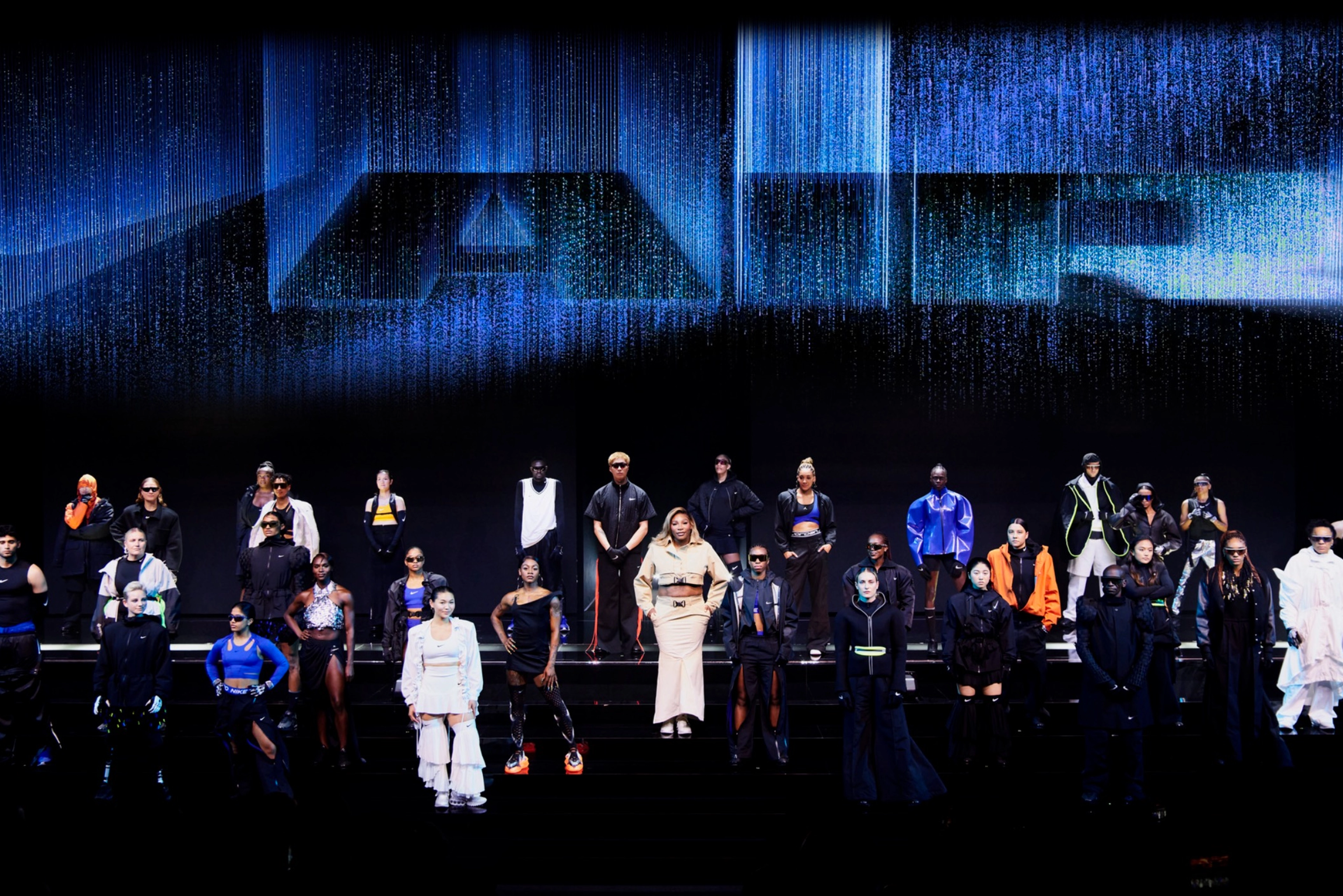Athletes pose on a large stage wearing newly unveiled Nike products.