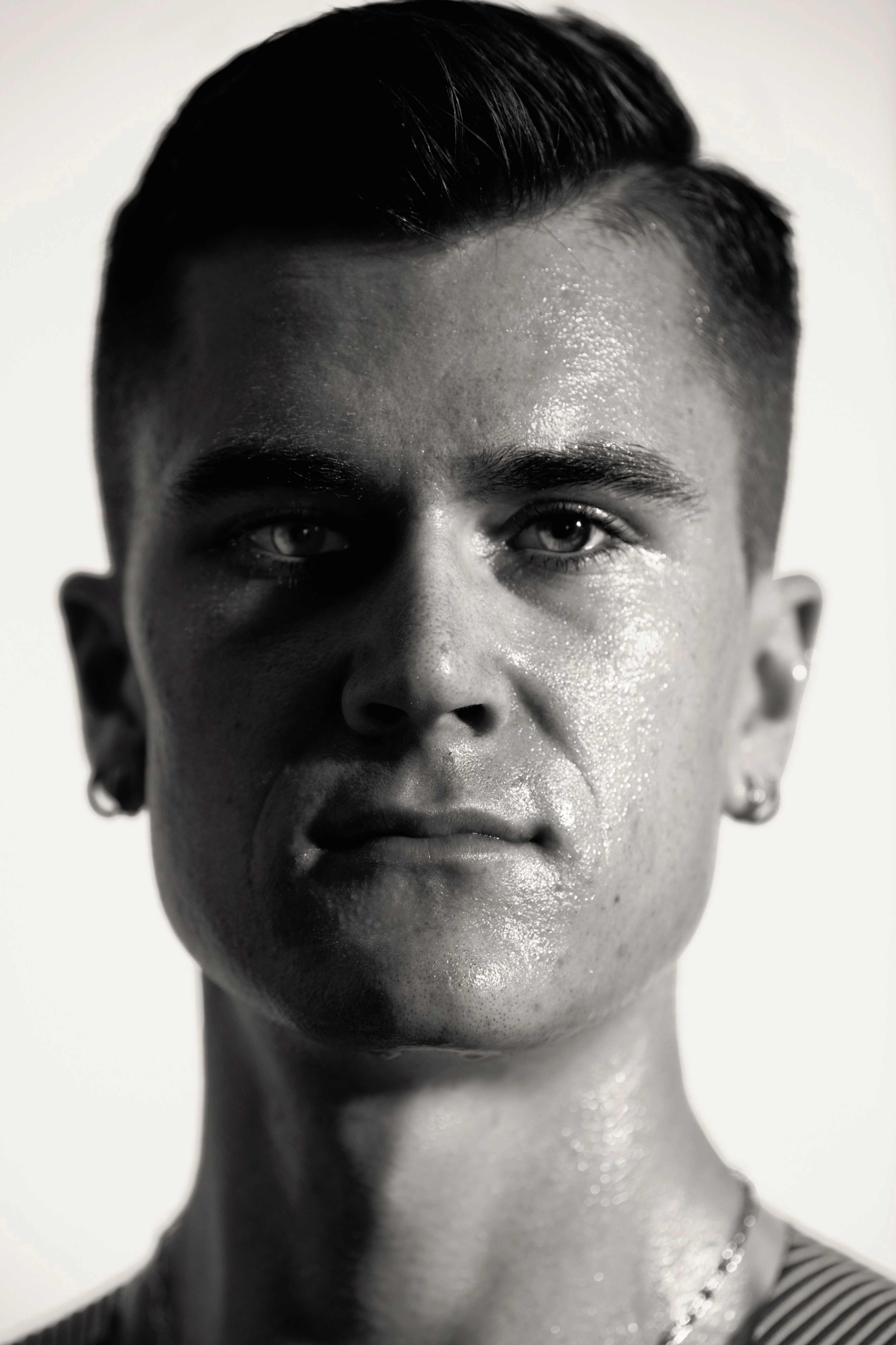 Black and white close up photo of Jacob Ingebrigtsen's face. His face is partly covered in shadow, as he looks unsmiling directly at the camera.