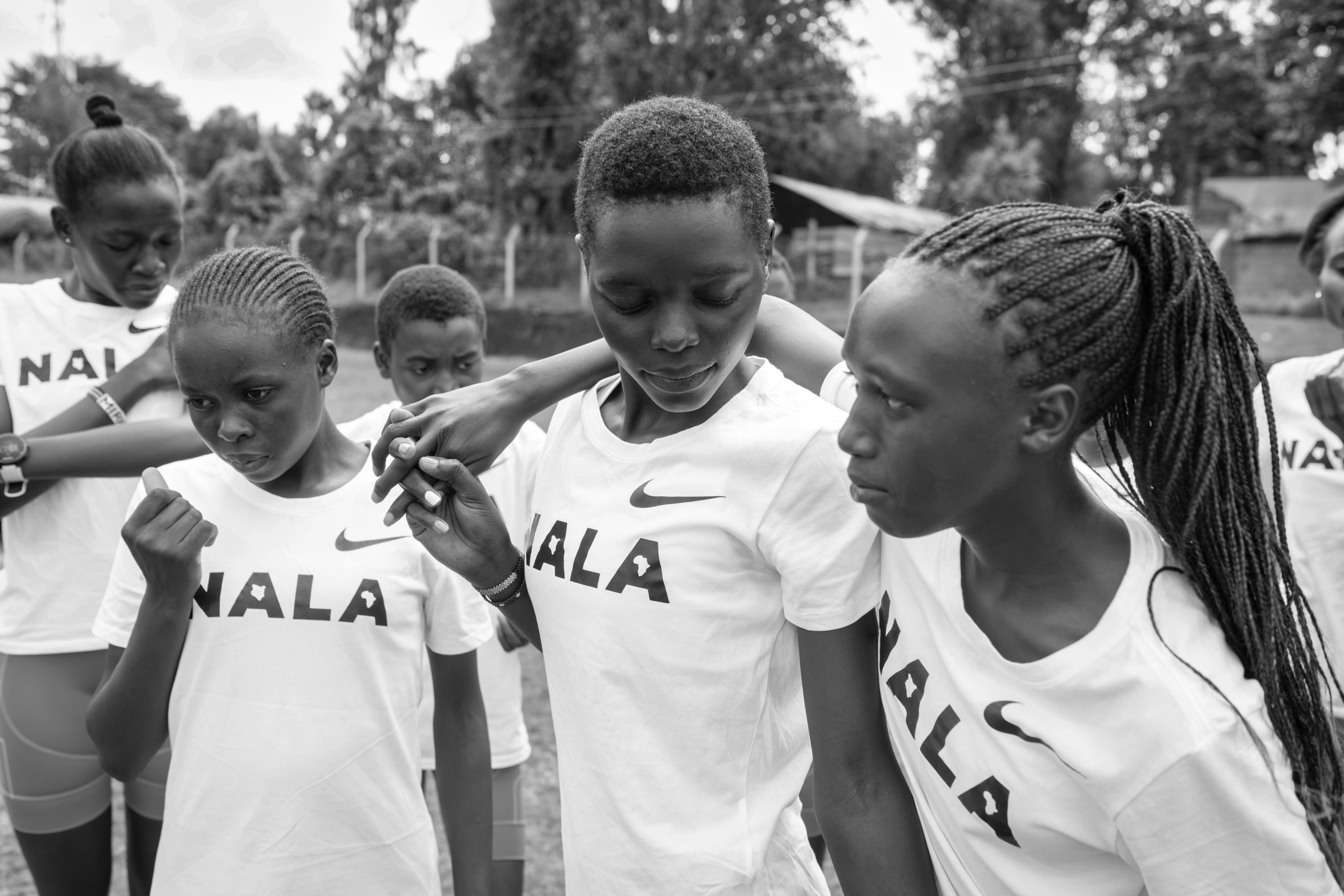 Black and white photo of Nala Track Club members wearing Nala t-shirts casually relaxing together at the track.