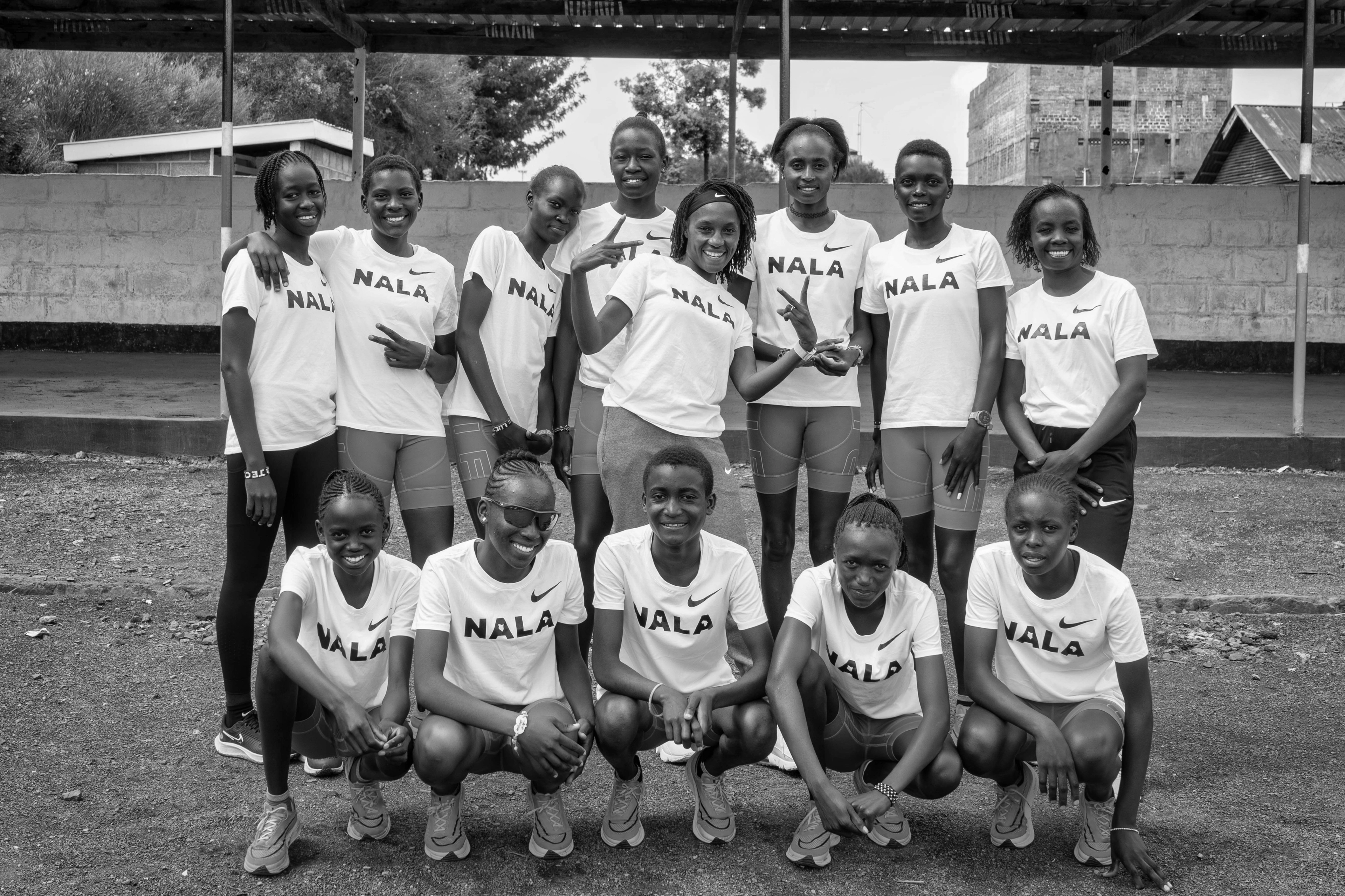 Black and white team photo of Nala Track Club members smiling and wearing Nala t-shirts.