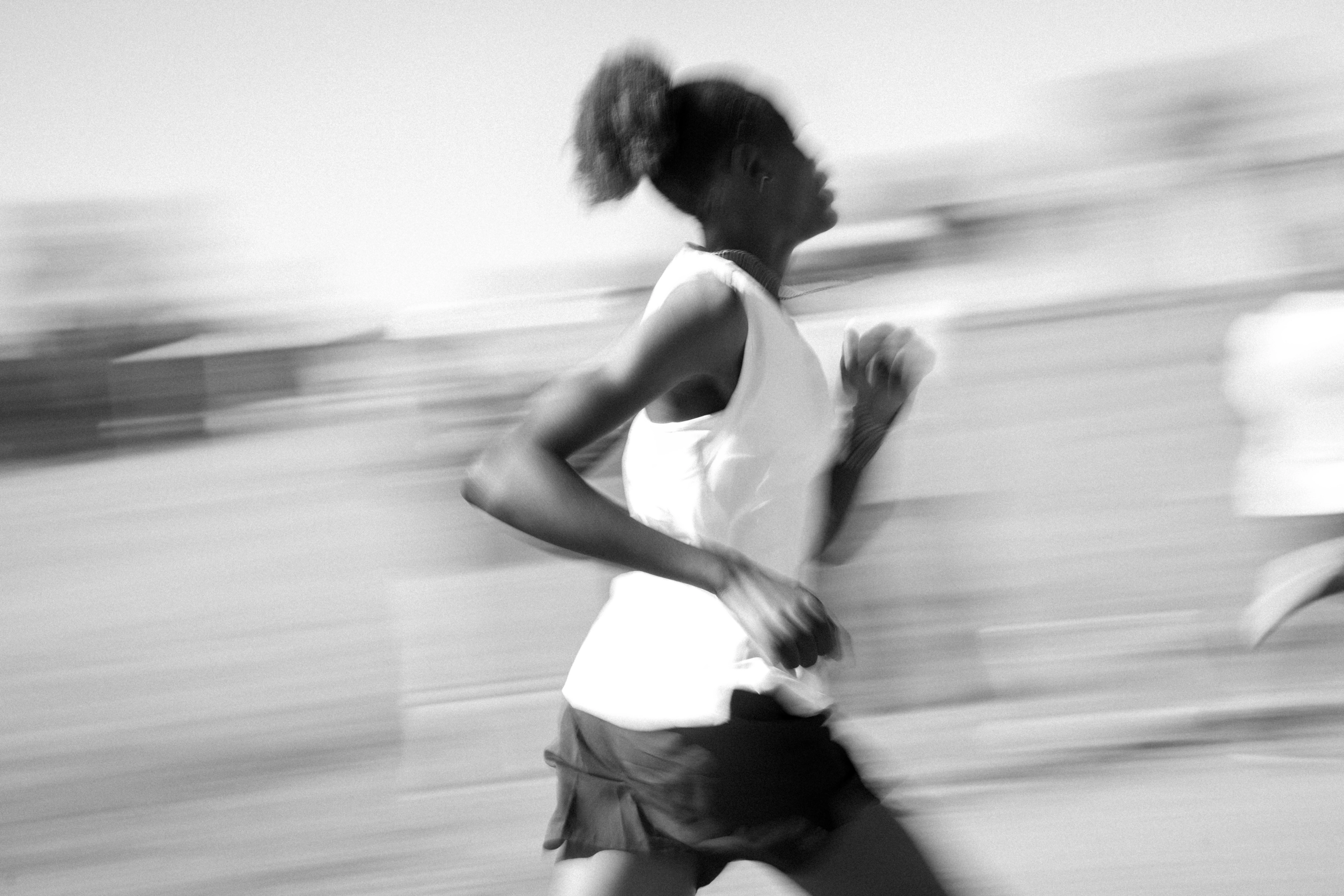 Black and white photo of Nala Track Club runner running on a blurred background.
